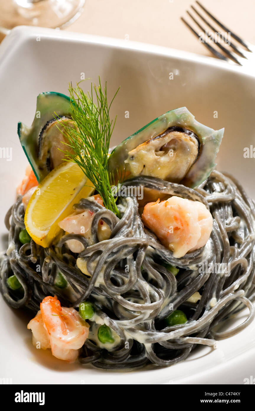 fresh seafood black squid ink coulored spaghetti pasta tipycal italian food Stock Photo