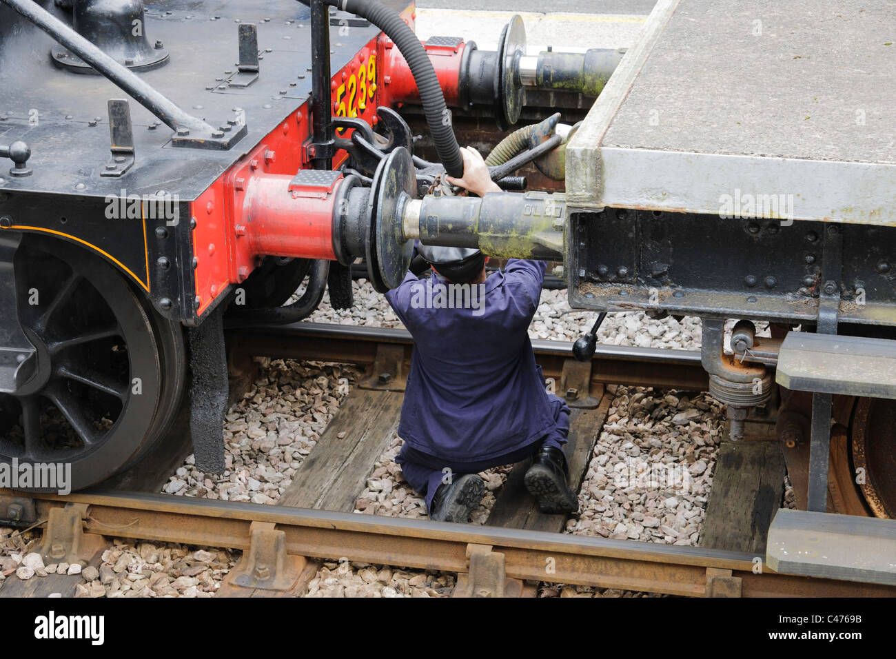 Rail worker coupling steam locomotive to train Stock Photo