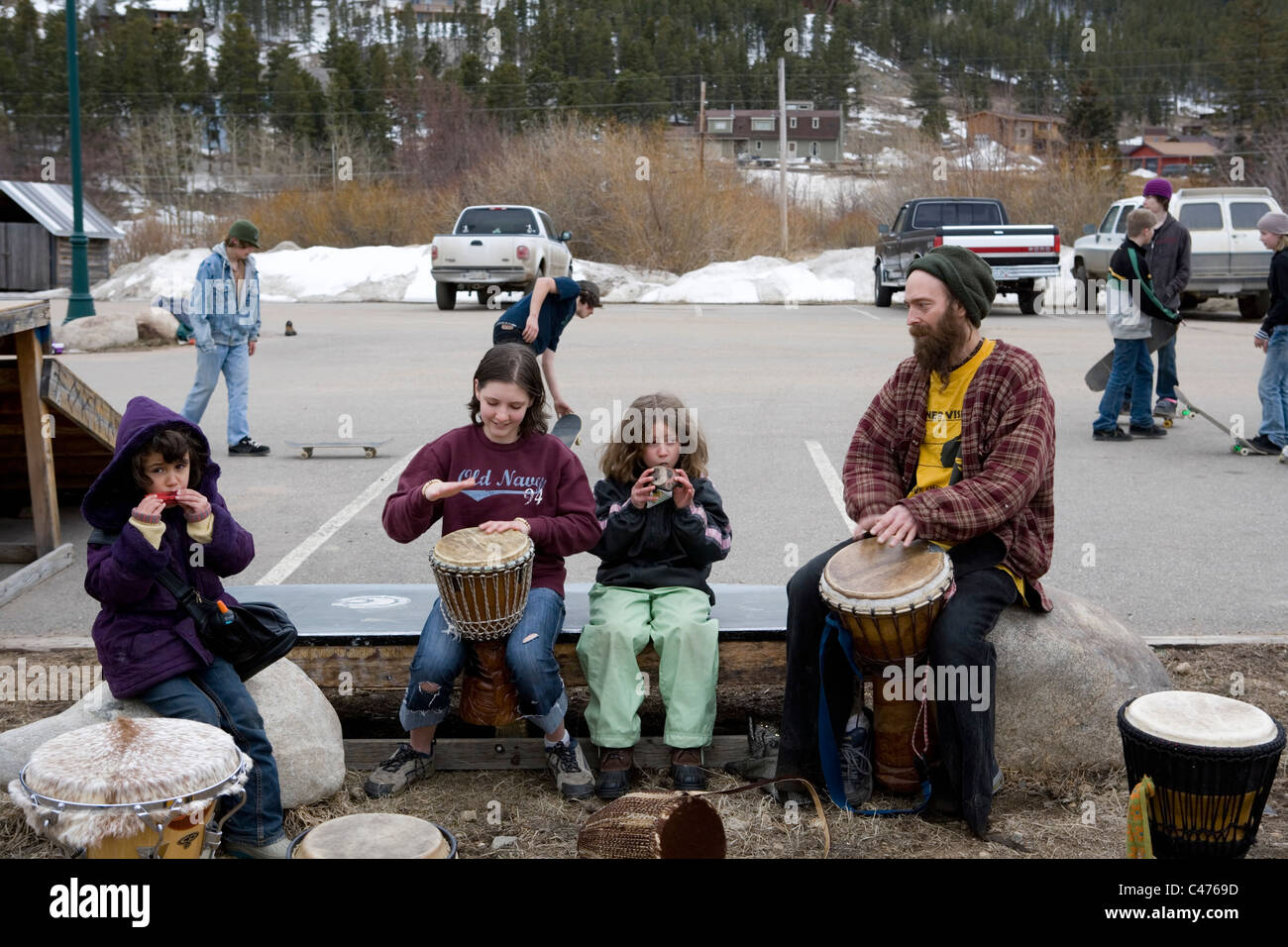 A family of hippies plays drums in a park during the Frozen Dead Guy