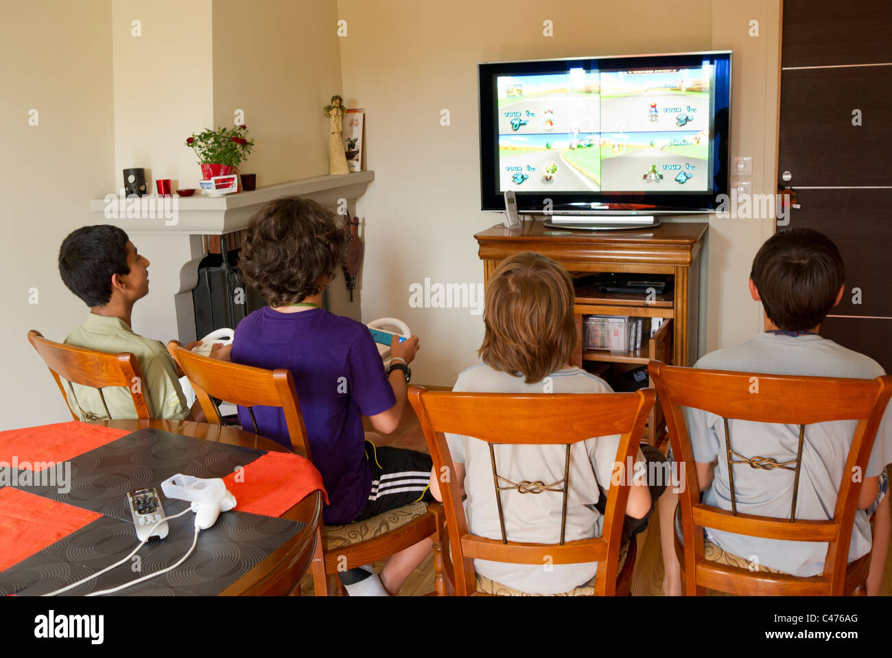 4 young teenages play Wii Nintendo console games Stock Photo