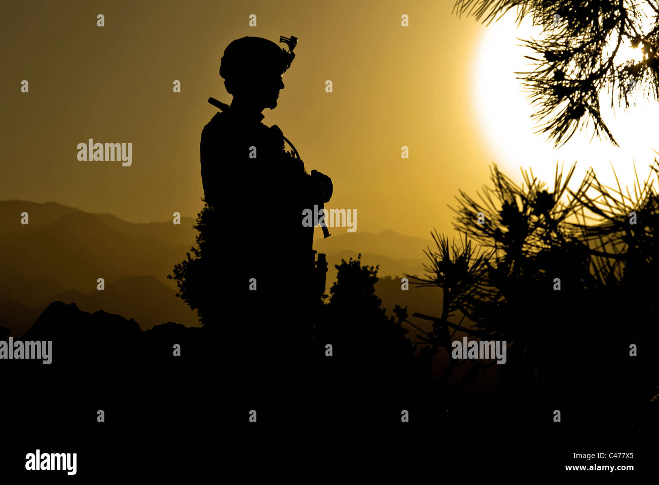 U.S. Army Sgt. Richard Toon is silhouetted against the setting sun during patrol along the Afghan Pakistan border Stock Photo