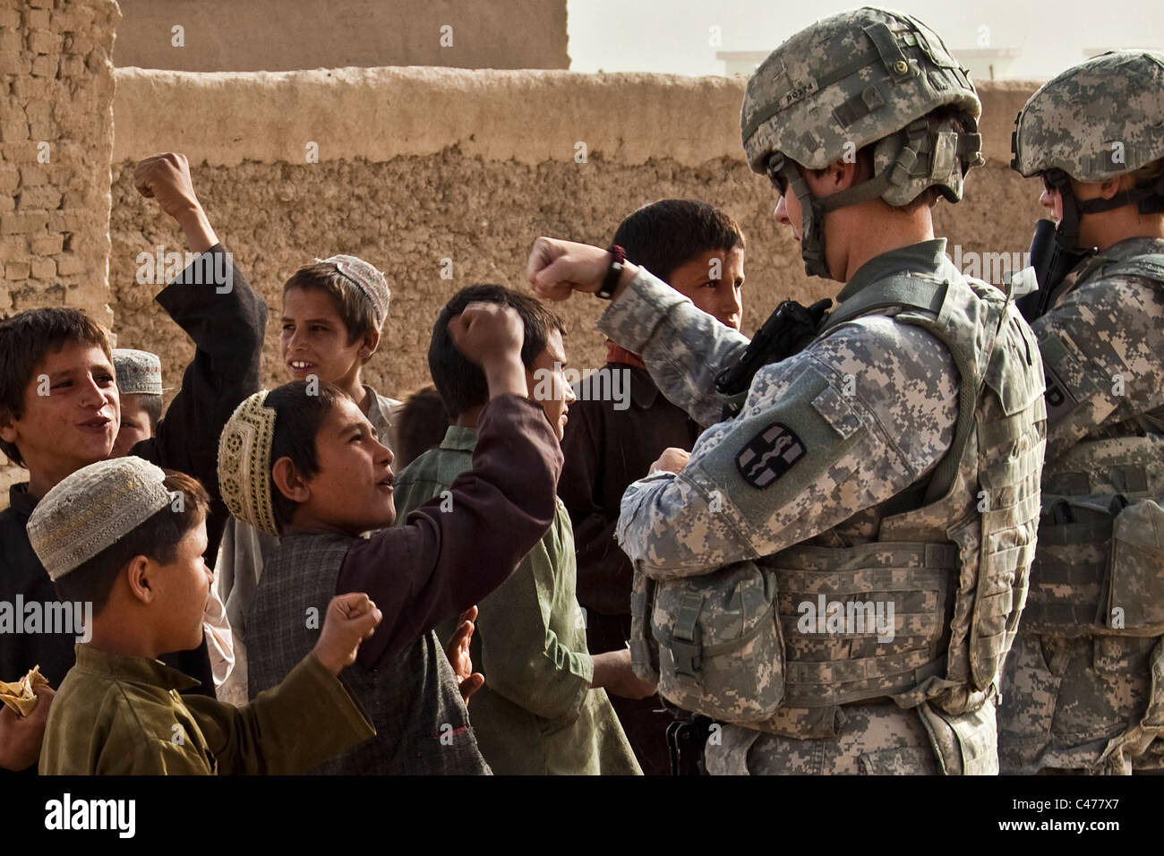 A group of local Afghan children bump fists with U.S. Army soldiers during a mission to Kuchi village, Afghanistan Stock Photo
