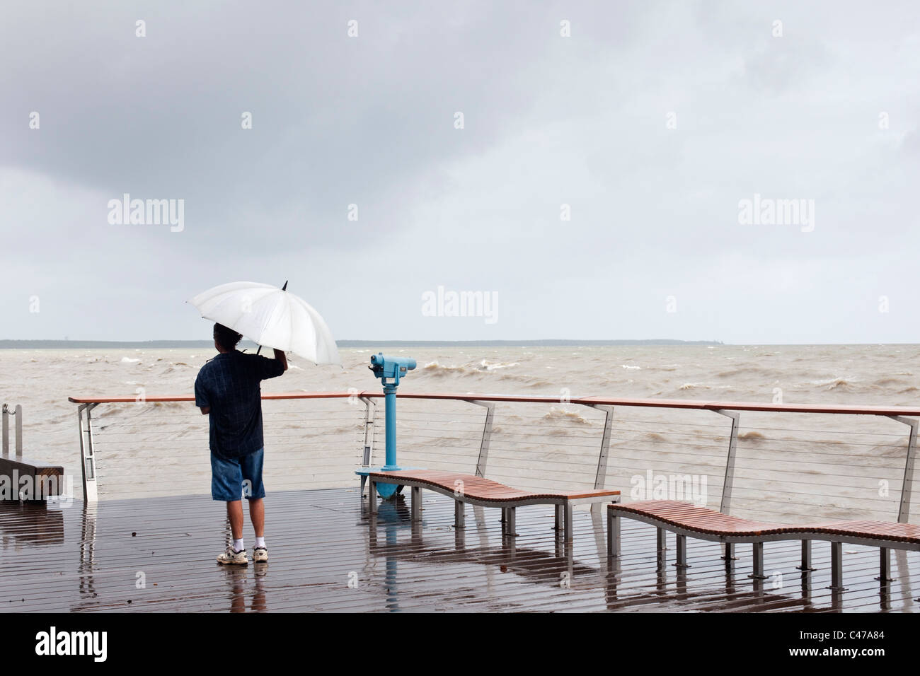 A man stands on the Esplanade boardwalk during stormy weather. Cairns, Queensland, Australia Stock Photo