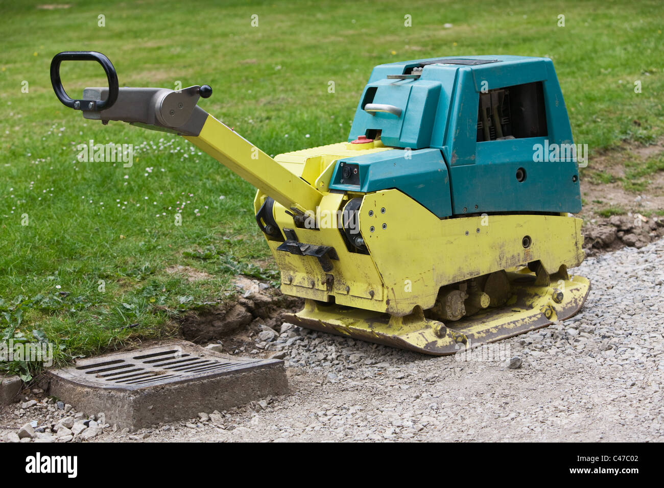 Vibratory plate compactor and manhole under construction Stock Photo