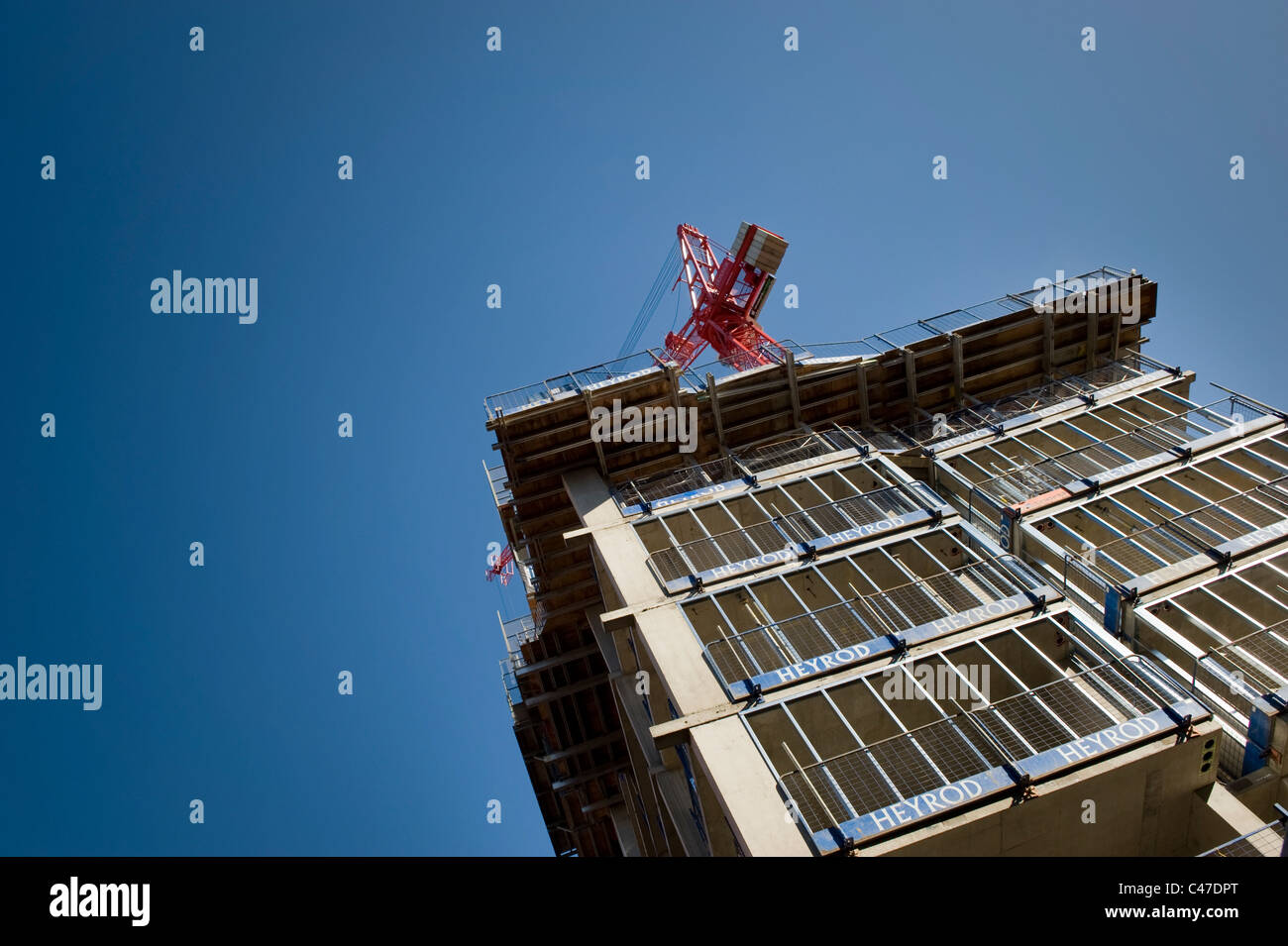 A building in construction by the company Heyrod, shot with a crane against a clear blue cloudless sky. Stock Photo
