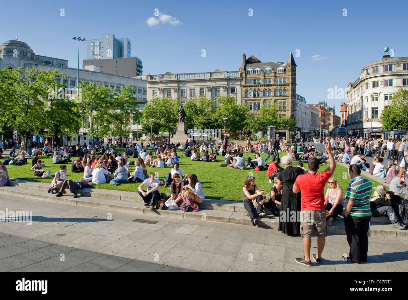 People congregate in the crowded Piccadilly Gardens, Manchester on a hot, sunny day. Stock Photo