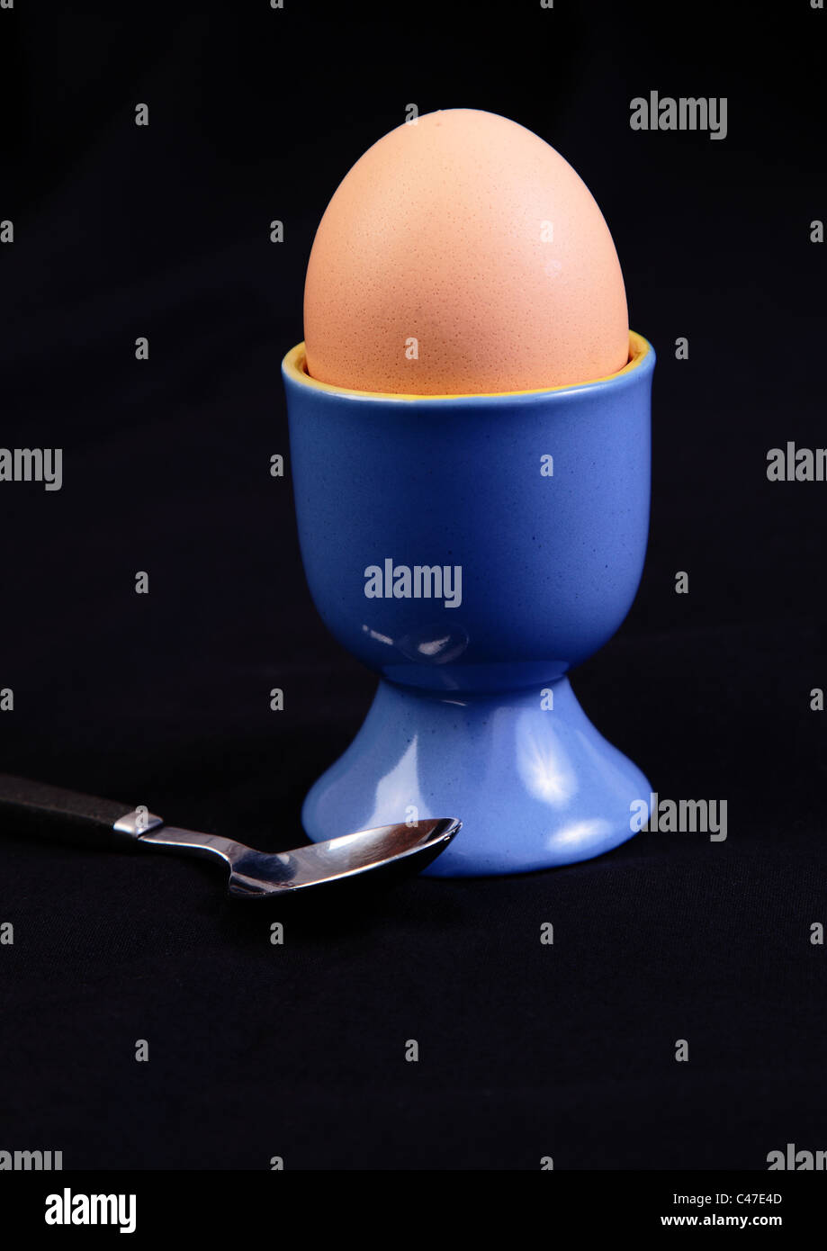 hard boiled egg in blue egg cup with spoon on black background Stock Photo Alamy