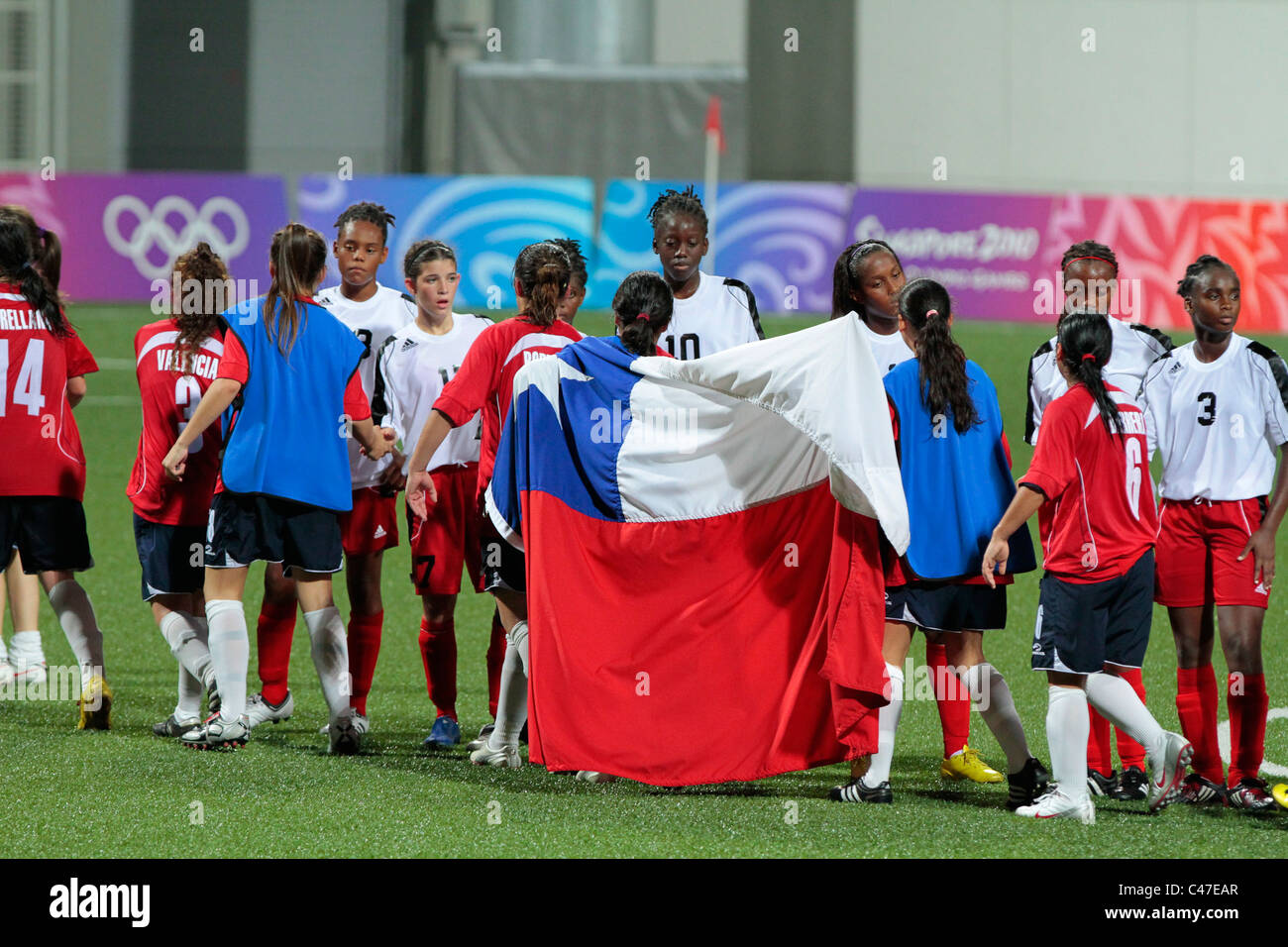 The Chilean flag is held up by the players as they shake hands with the Trinidad & Tobago players after the match. Stock Photo