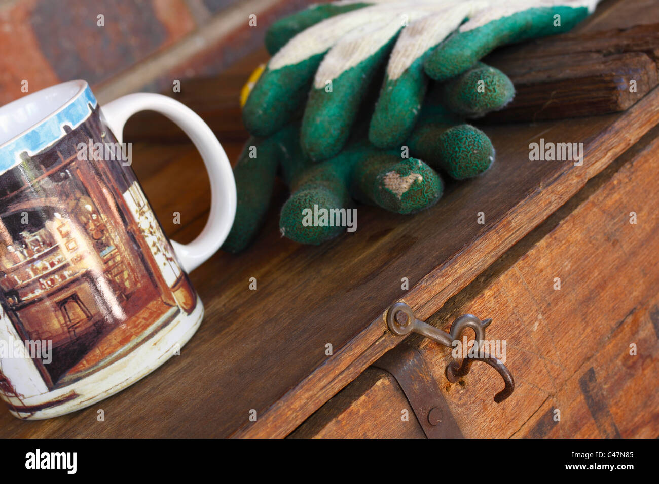 Coffee cup and gardening gloves on a wooden chest. Teabreak, coffee break. Stock Photo