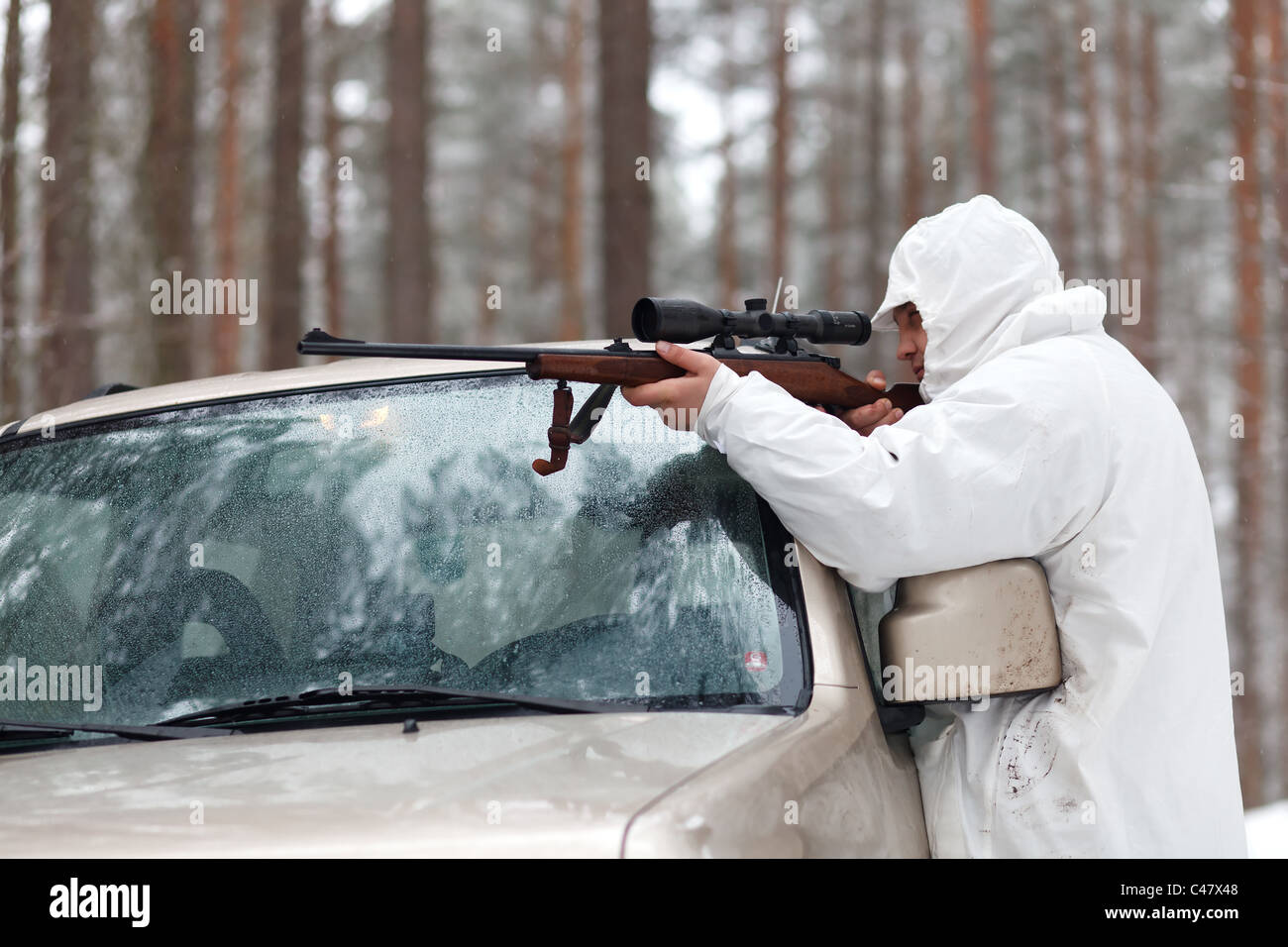 Sniper in white camouflage on jeep at winter forest. Stock Photo