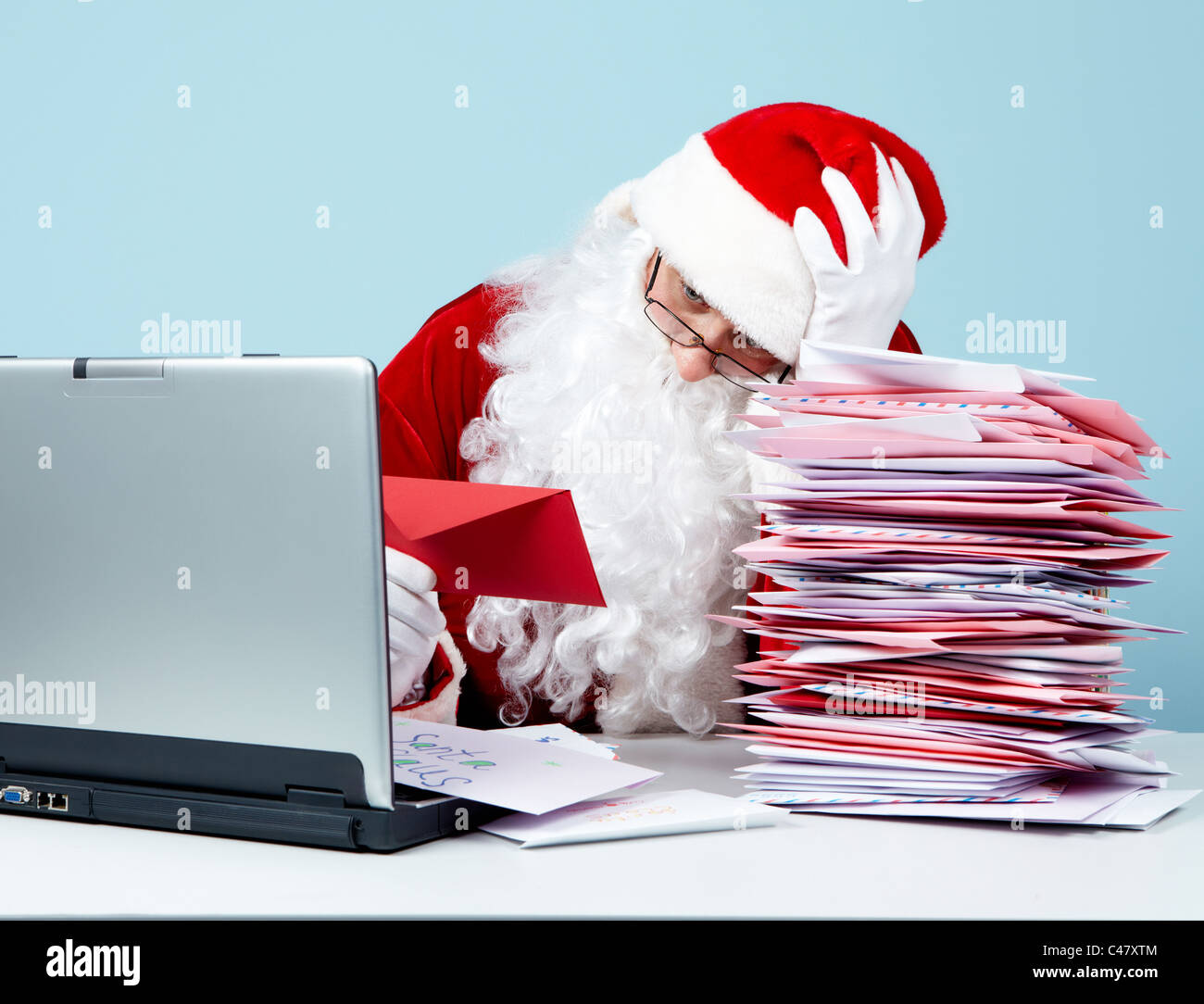 Portrait of confused Santa Claus touching head while looking at letter in front of laptop Stock Photo