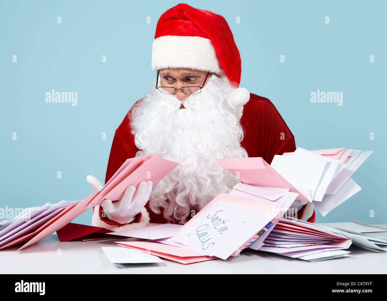 Image of Santa Claus looking at heap of letters with terrified expression Stock Photo