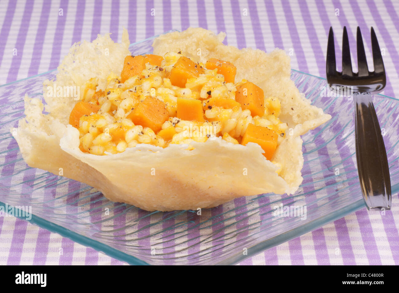 Cheese basket filled with risotto and pumpkin over a glass dish Stock Photo