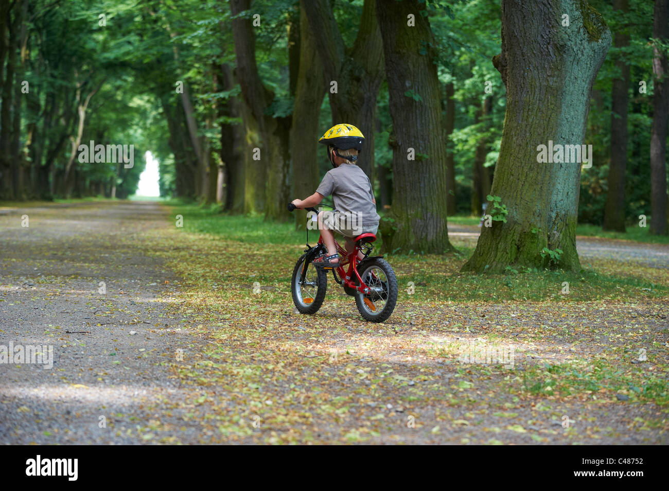 Child blond boy 4 years old riding bicycle with safety helmet in park