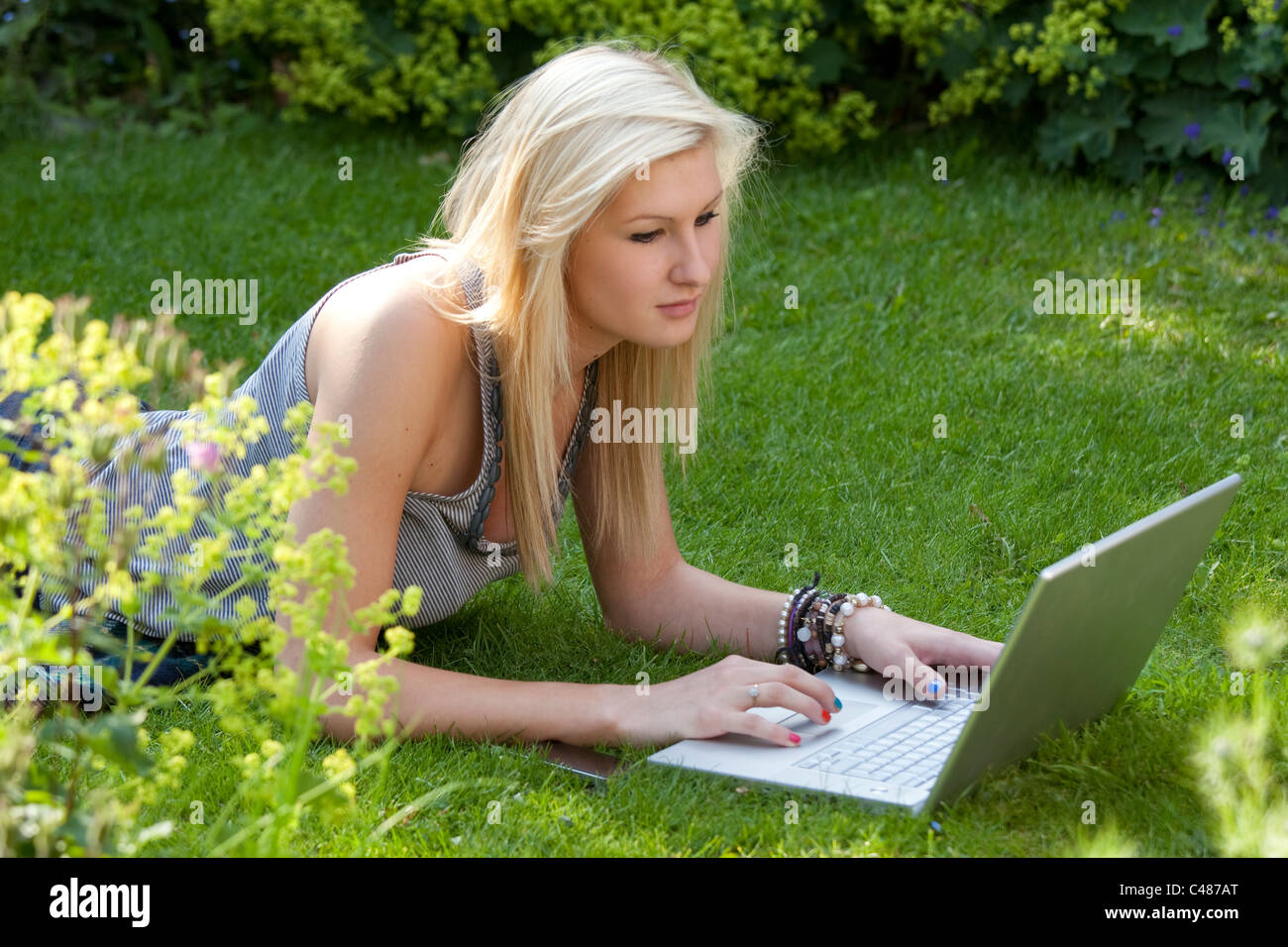 Young girl on laptop in the garden surfing the internet Stock Photo
