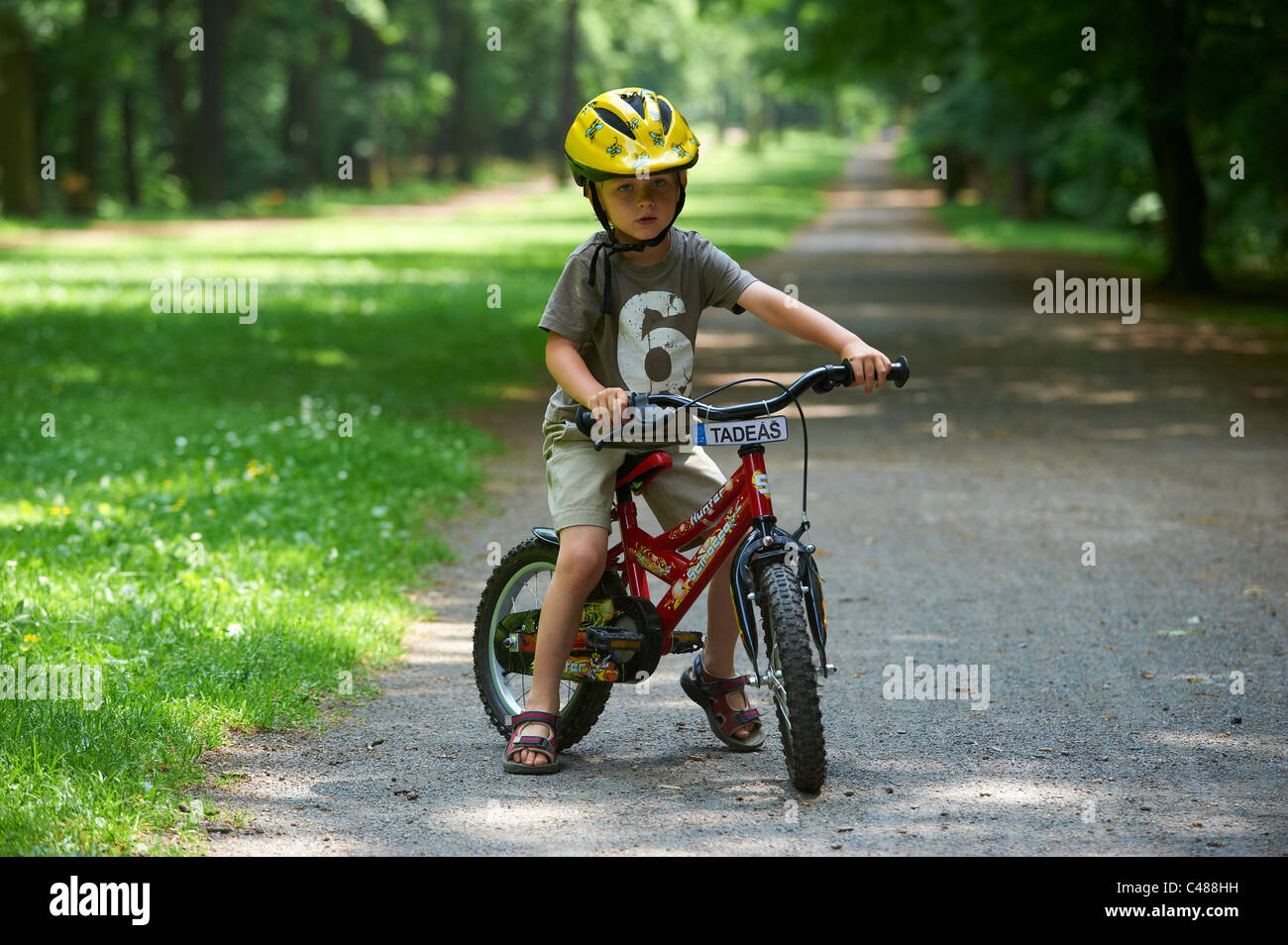 Child blond boy 4 years old riding bicycle with safety helmet in park