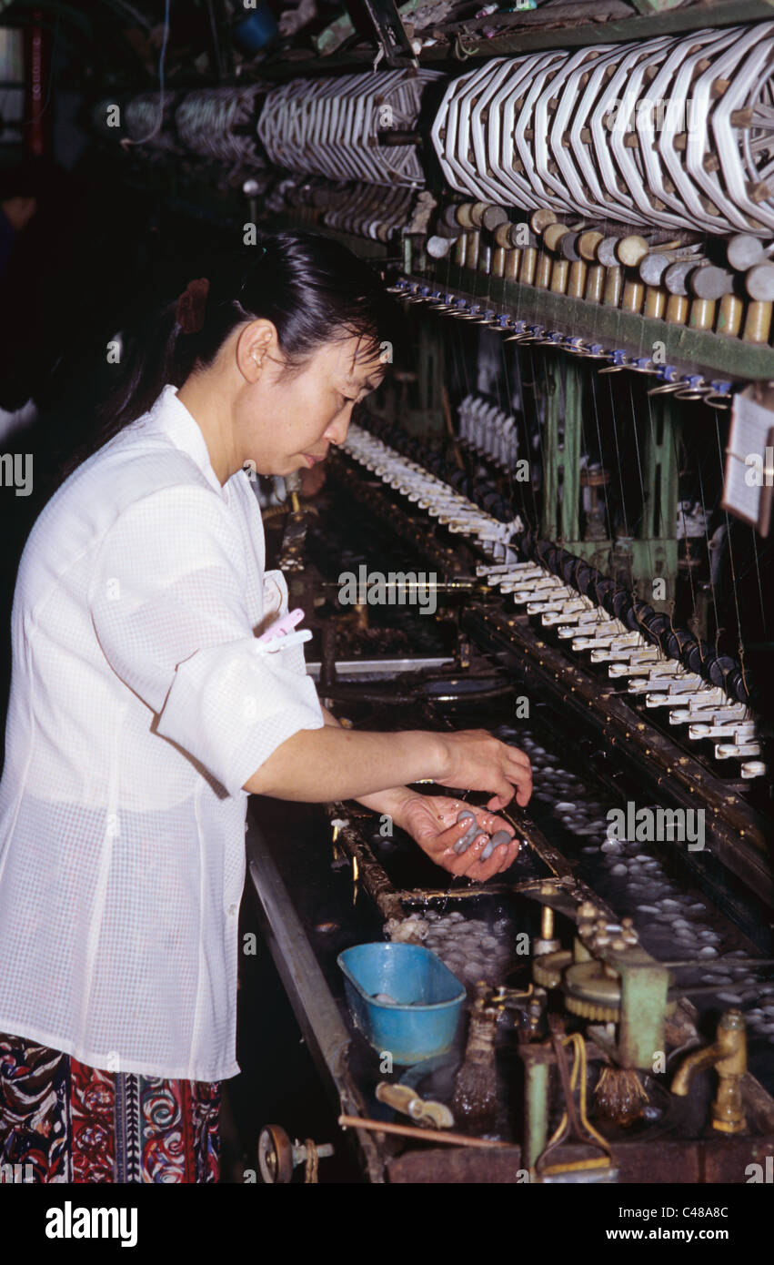 Making silk thread by combining the silk from six cocoons, Suzhou, China 990523 0418 Stock Photo