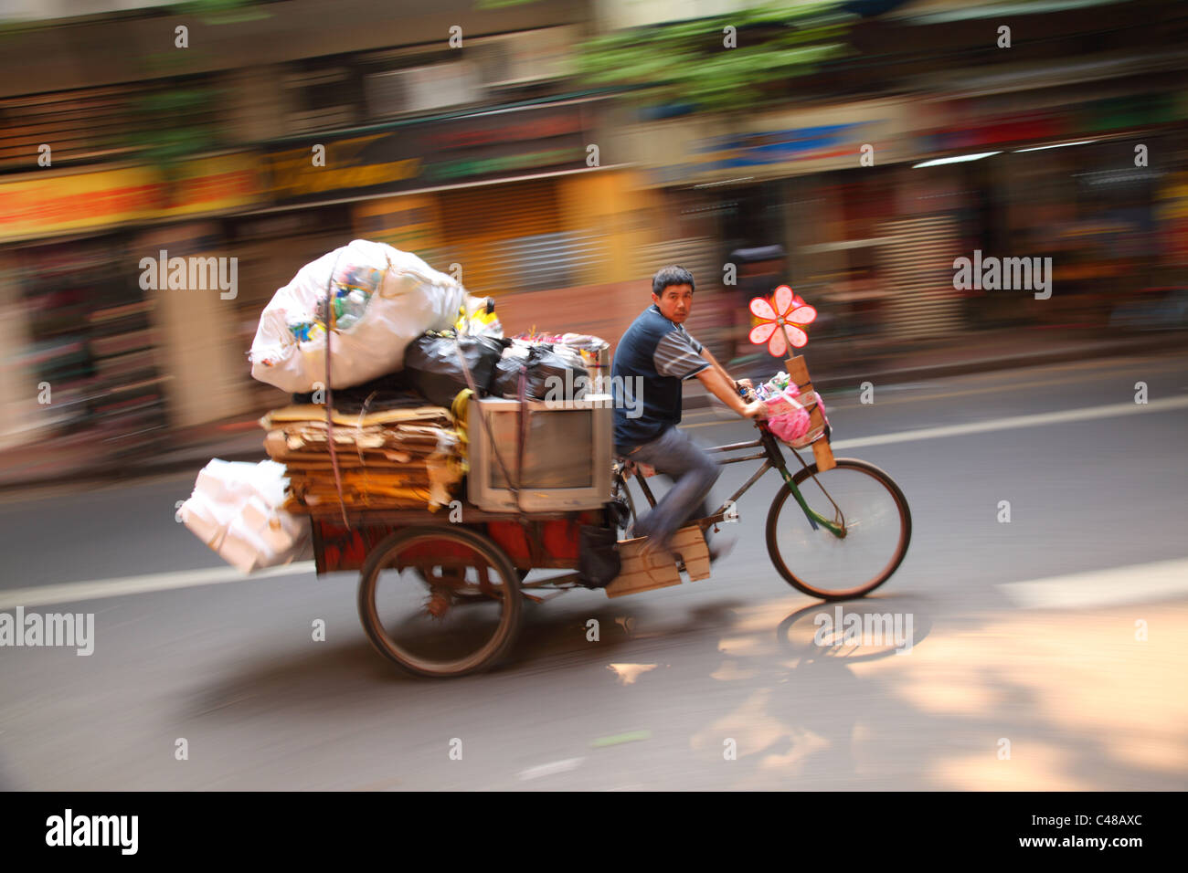 Man rides overloaded rickshaw, Guangzhou, China Stock Photo