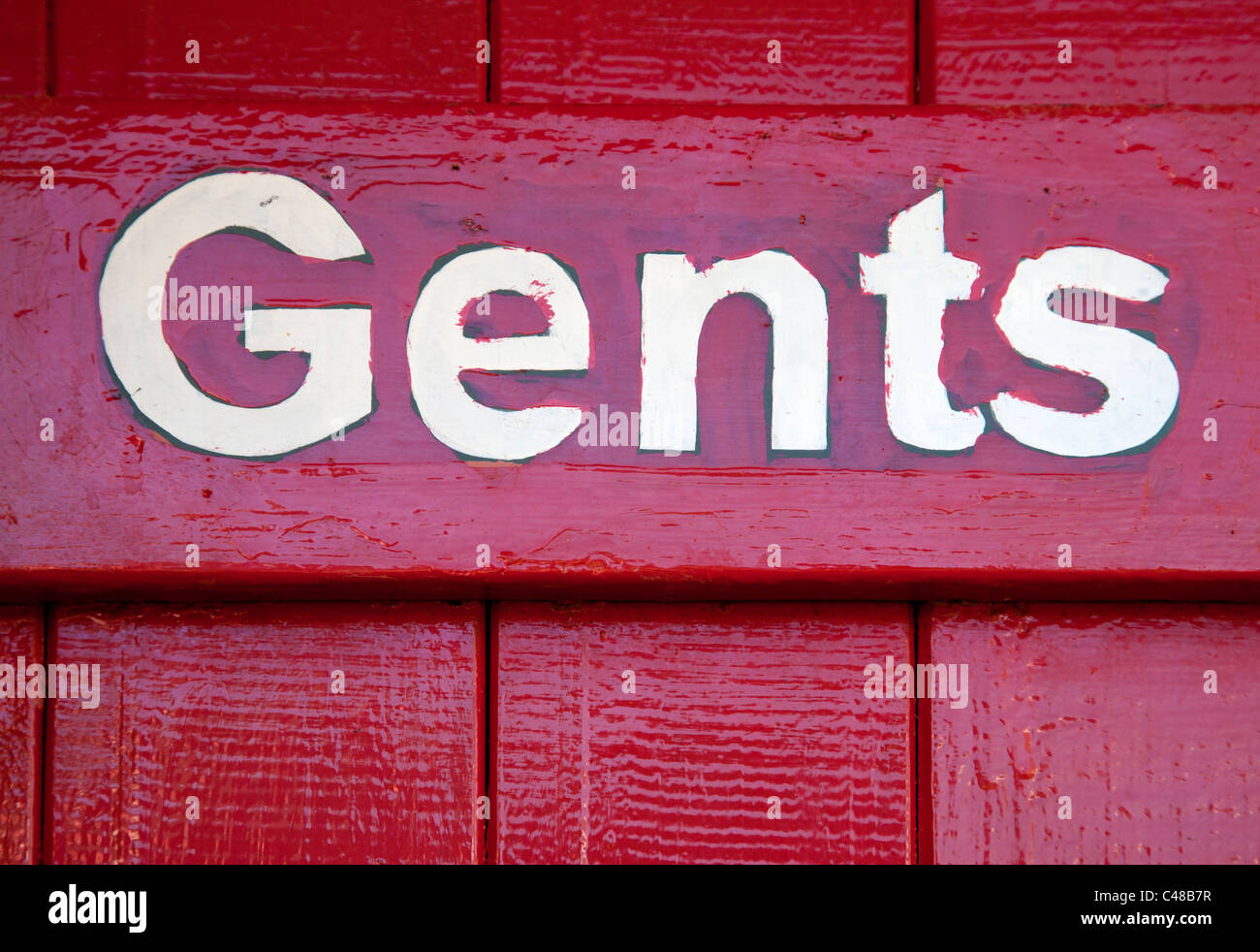 Gents toilet sign painted on red door Stock Photo