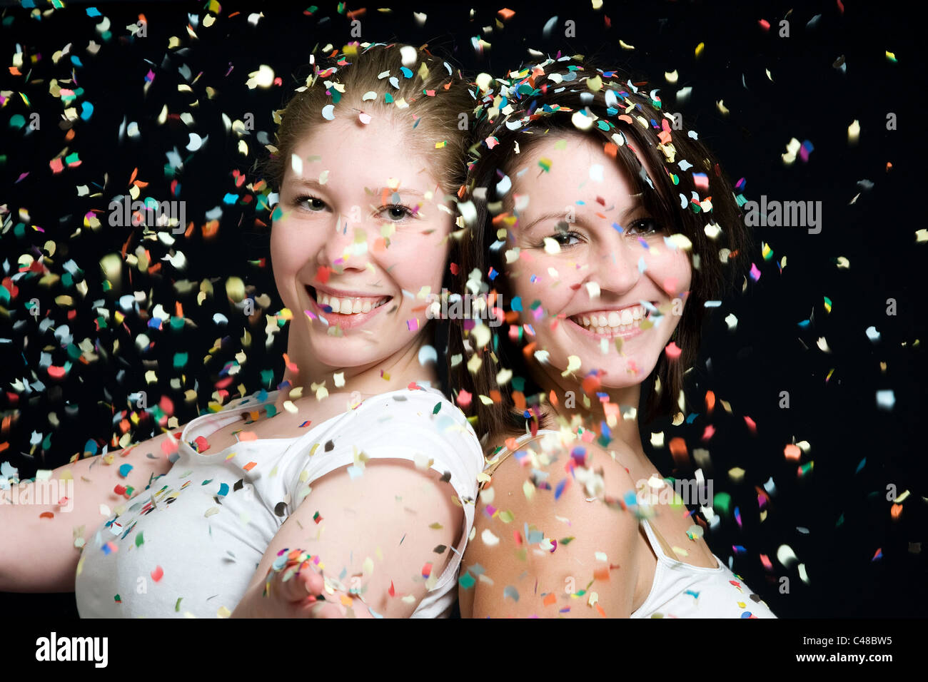 Two young women throwing confetti Stock Photo Alamy
