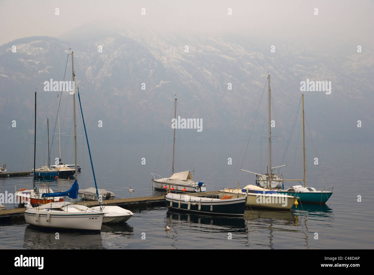 Moorage with boats against Lake Como at Tremezzo. Lombardy. Italy. Winter. Stock Photo
