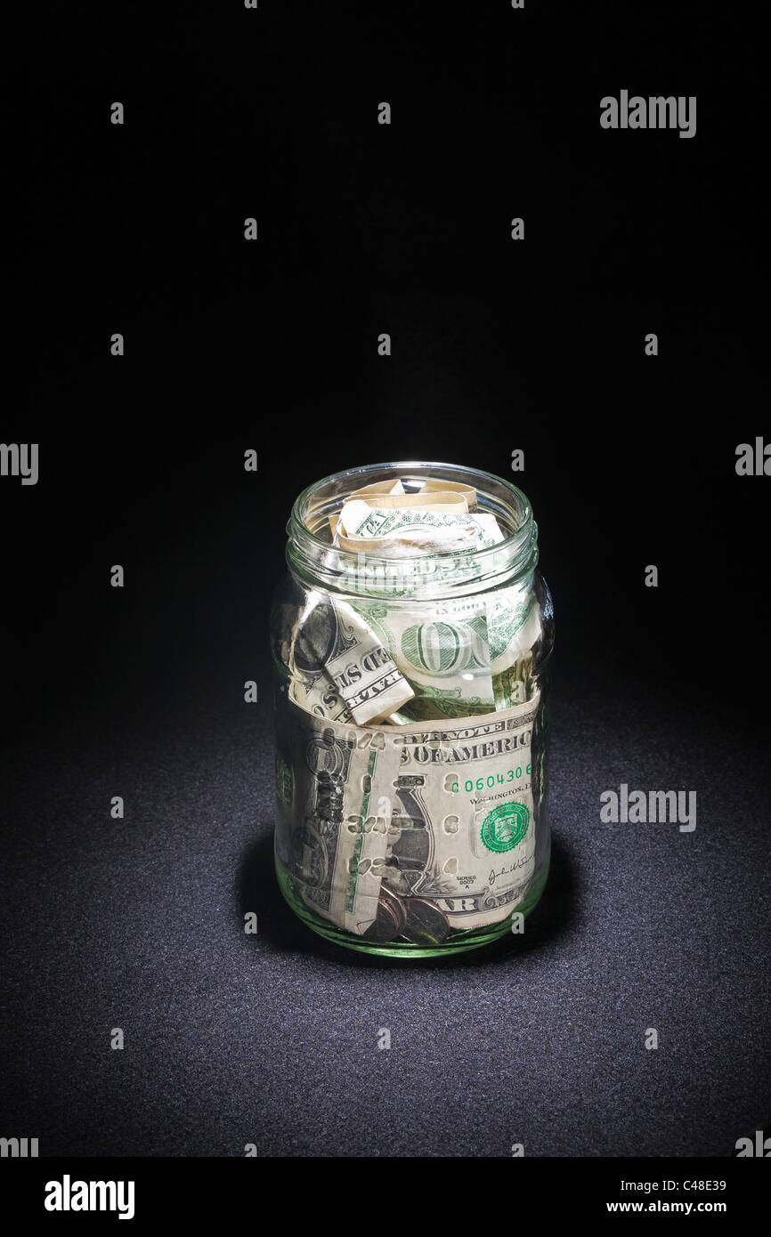 tips jar containing us currency in coins and paper dollar bills Stock