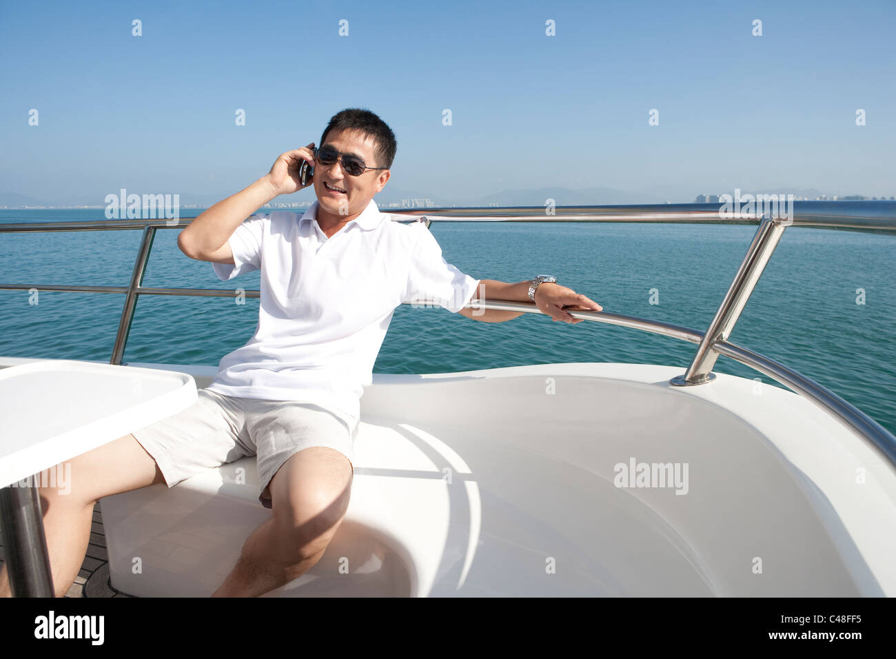 Carefree Man Talking on the Phone While Yachting Stock Photo