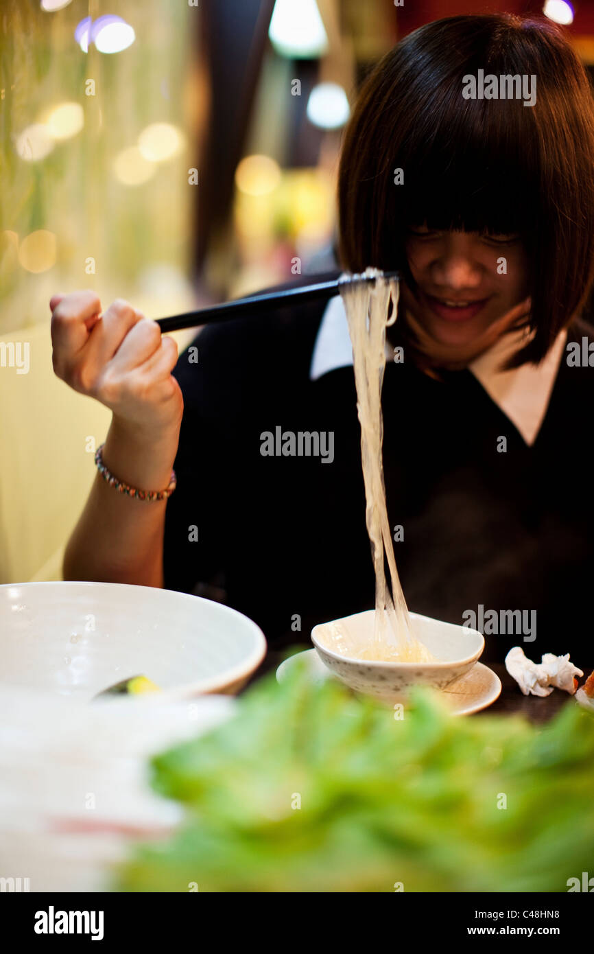 A teenage girl eats noodles at a hot pot restaurant, Taipei, Taiwan, November 8, 2010. Stock Photo