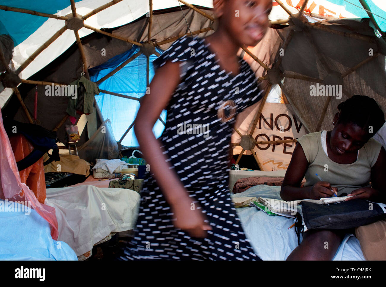 Girl doing her homework in her tent home in Port-au-Prince. Stock Photo