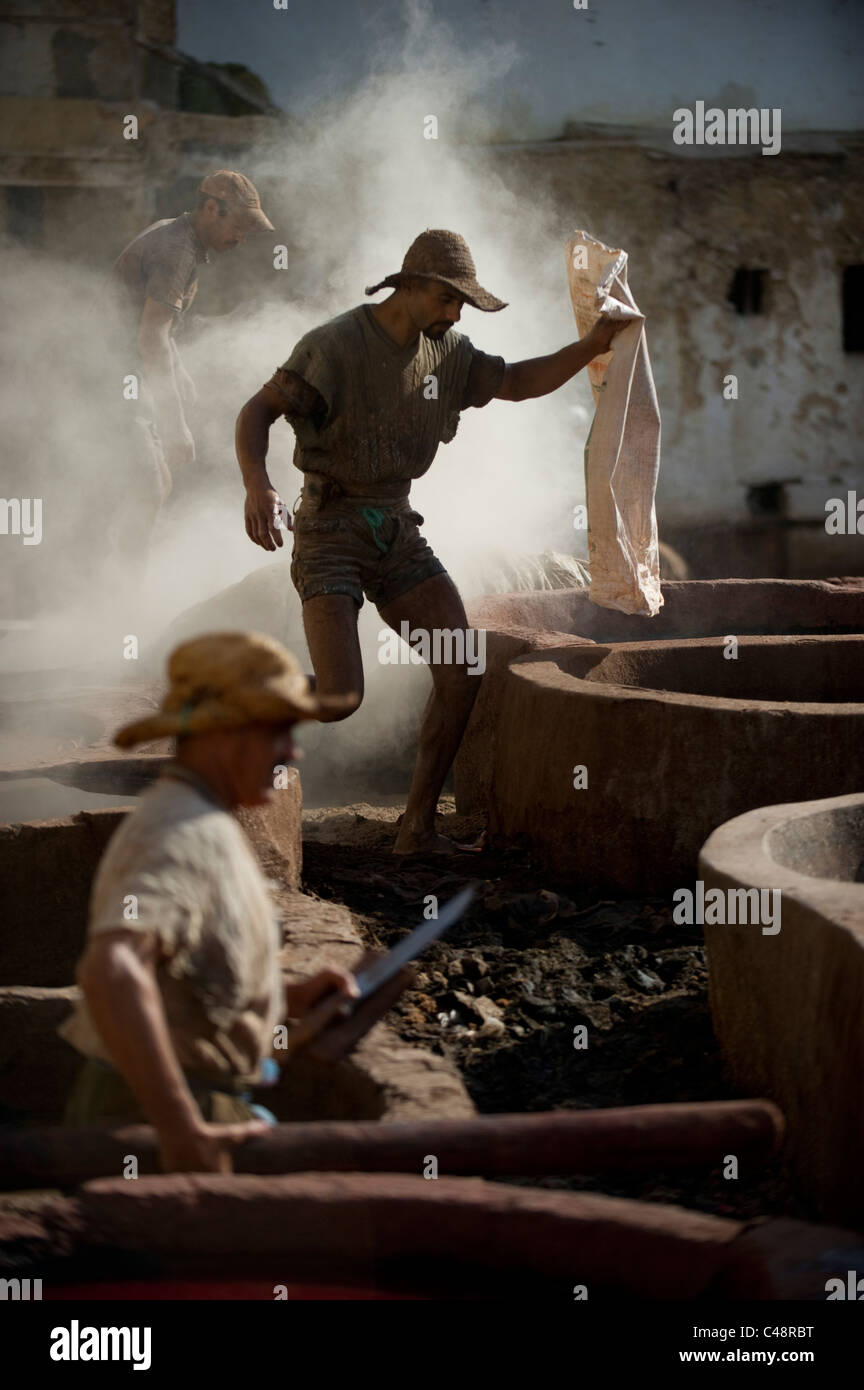 A man walks barefoot over the open pots of leather stains and dyes after  pouring toxic dye powder into one of the empty vats at Stock Photo - Alamy