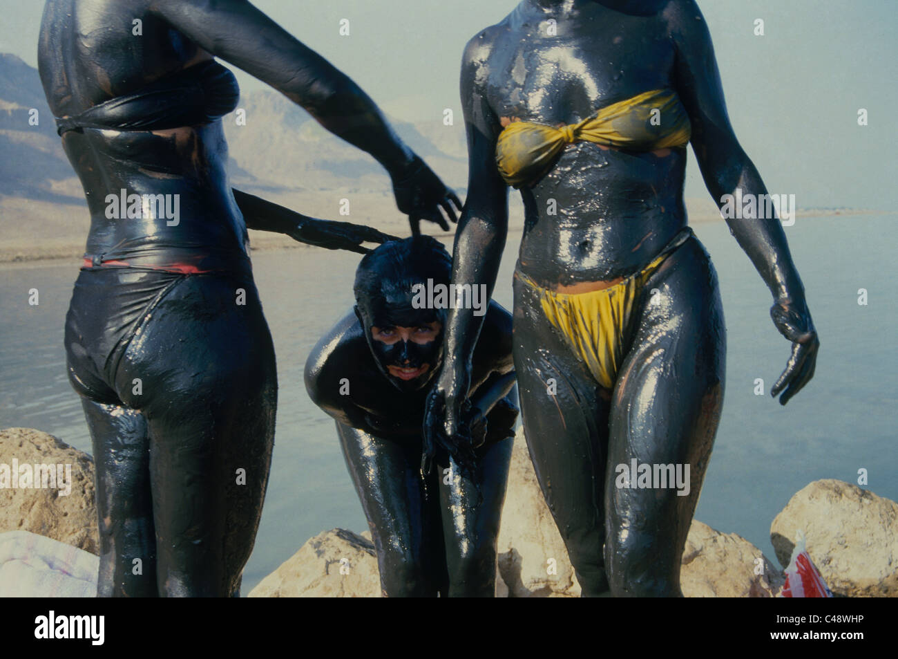 Tourists covered with the famous black mud from the Dead sea Stock