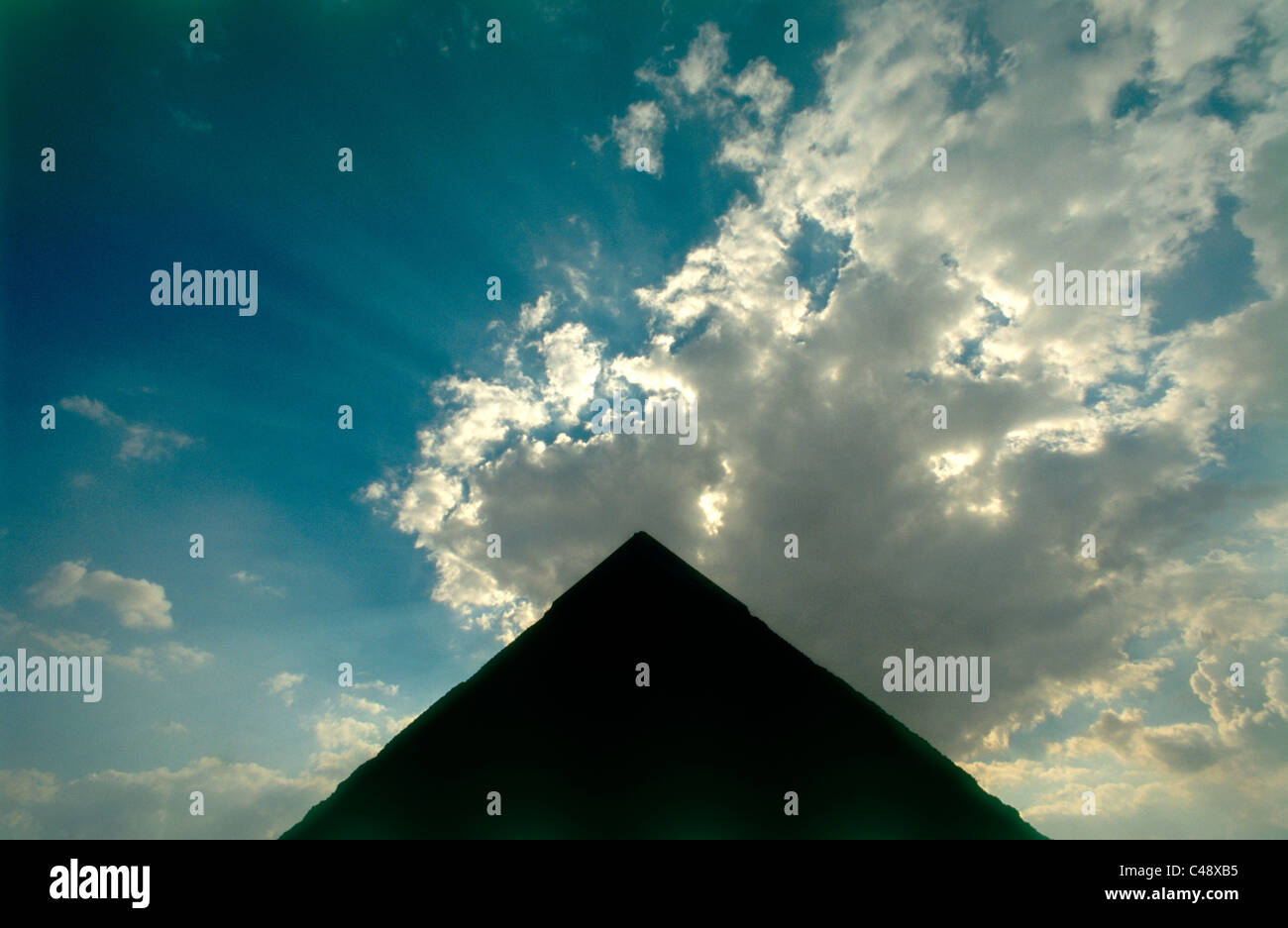 Photograph of the sun light emerging behind the pyramid's silhouette in Egypt Stock Photo