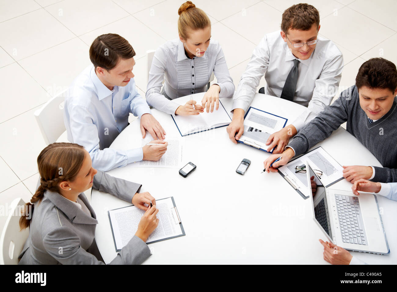 Image of company of successful partners looking at their colleague at meeting Stock Photo