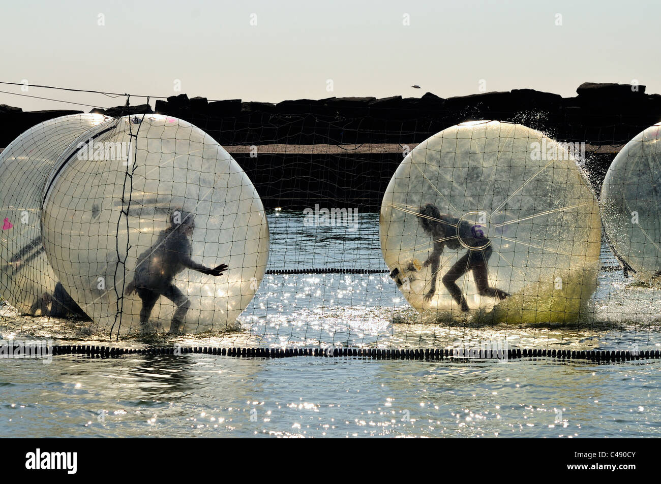 Children playing in zorbing balls on water Stock Photo
