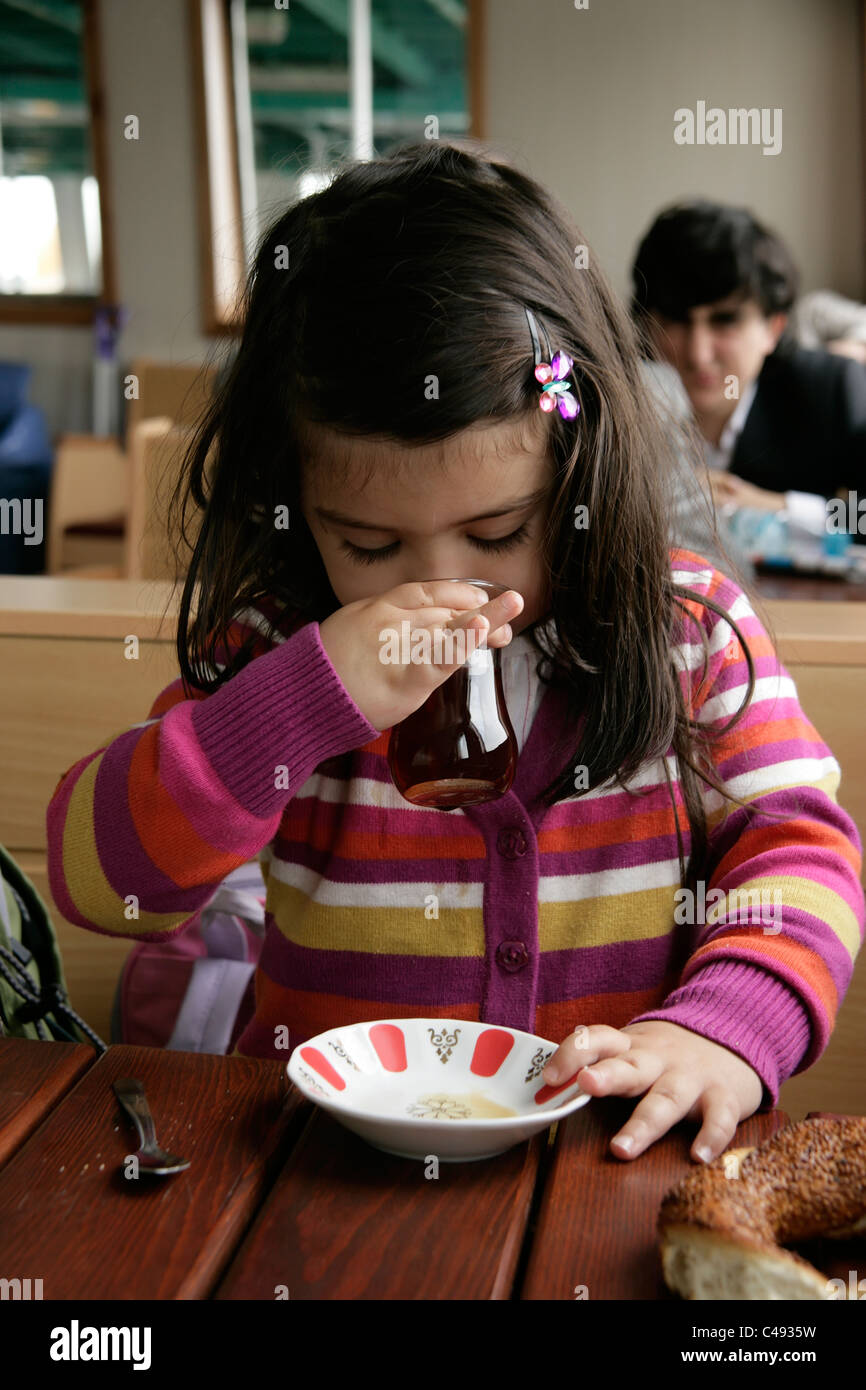 Three year old Turkish girl drinking tea on a ferry, Istanbul, Turkey Stock Photo