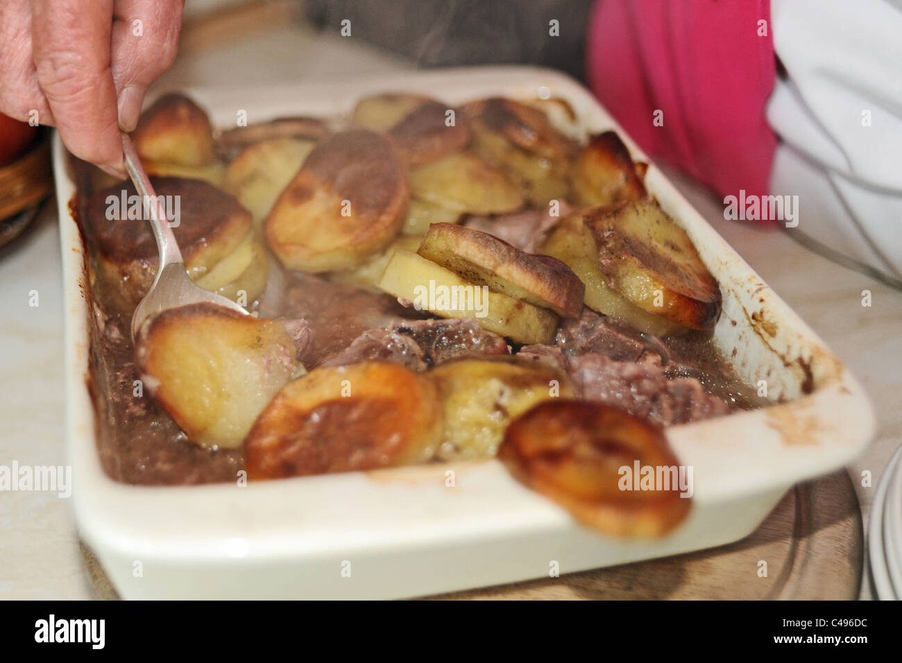 Female elderly OAP serving up a Lancashire Hot Pot for dinner UK Stock Photo