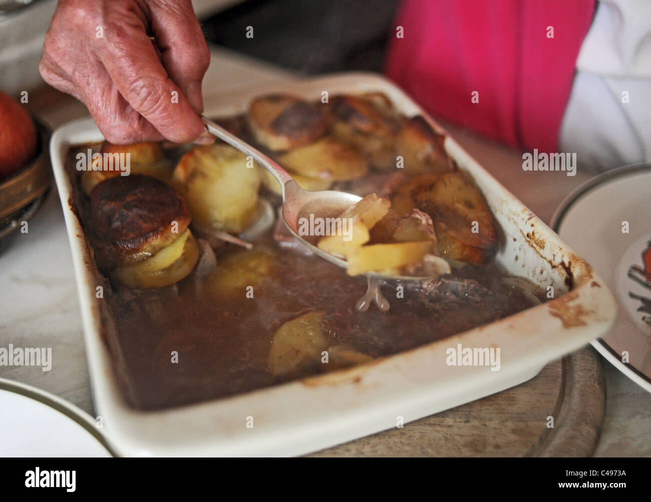 Female elderly OAP serving up a Lancashire Hot Pot for dinner UK Stock Photo