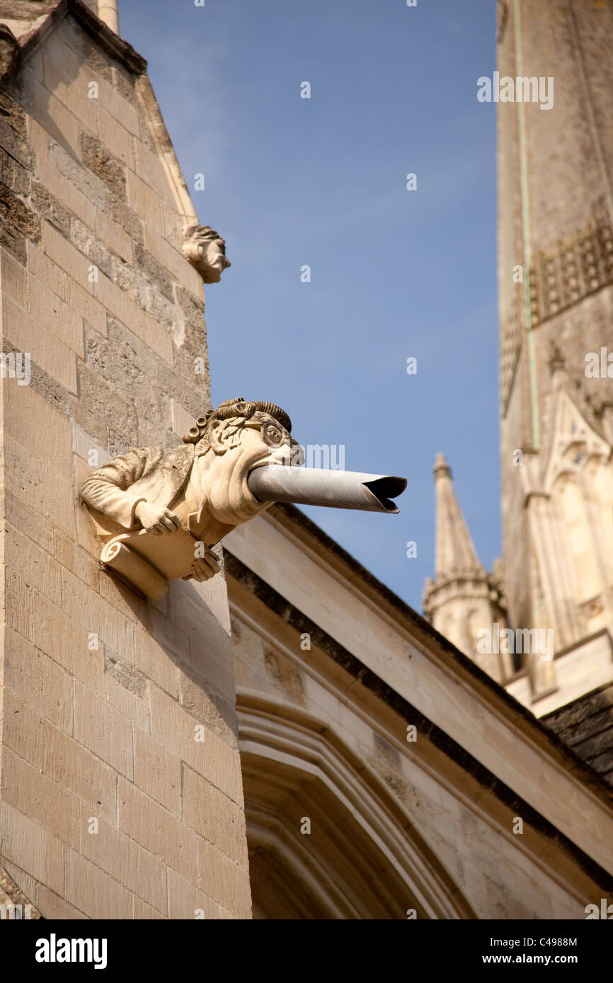 Gargoyle with wig and spectacles and metal evacuation pipe in his mouth Chichester Cathedral Sussex England Stock Photo