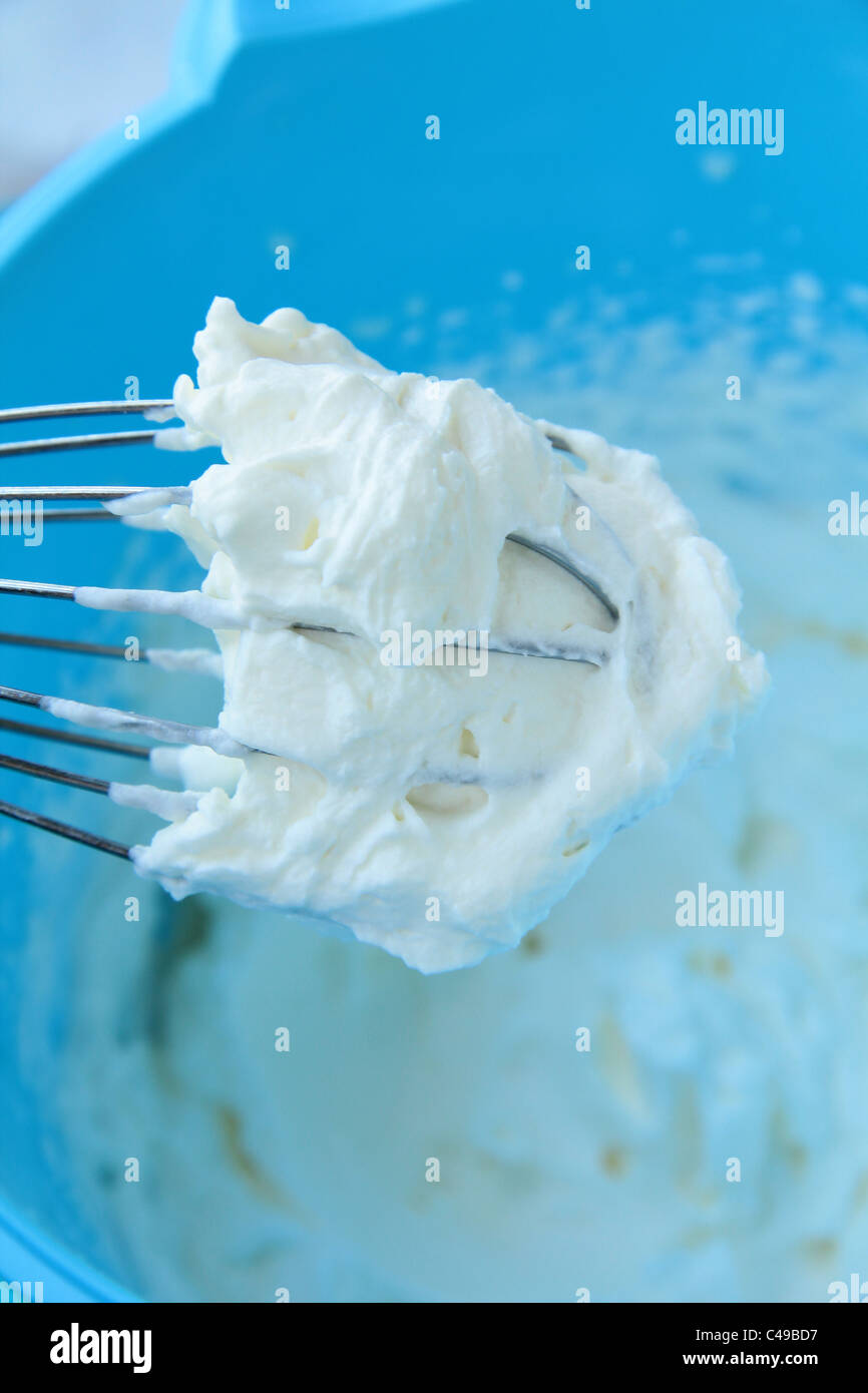 Beating a white cream with a mixer in a metal bowl. Whipped cream. Cream  for the cake Stock Photo - Alamy