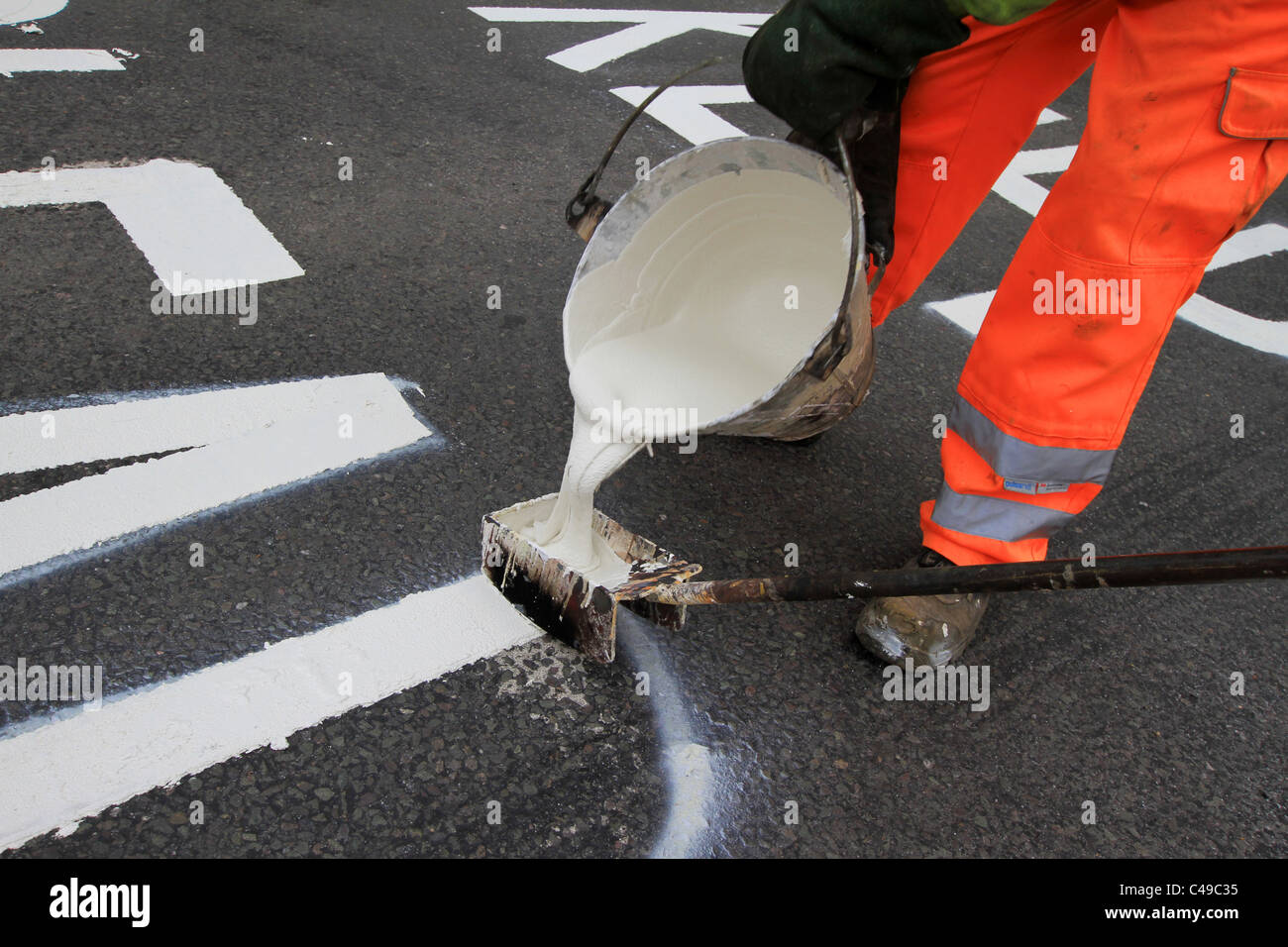 Road marking, road gang, keep clear, Health and Safety, painting road, Men at Work, trolly paint, line marking pram, following kerb line, yellow mark. Stock Photo