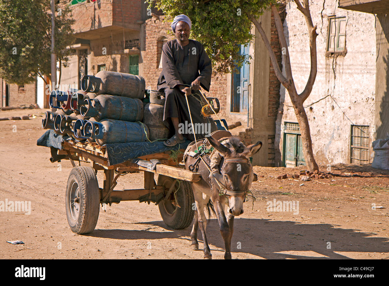 Luxor resident carries bottled gas cylinders on his carted pullled by a tired donkey Stock Photo