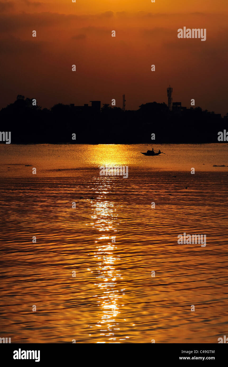 A small boat, setting sun, ripple over water of river Ganges (Hoogly
