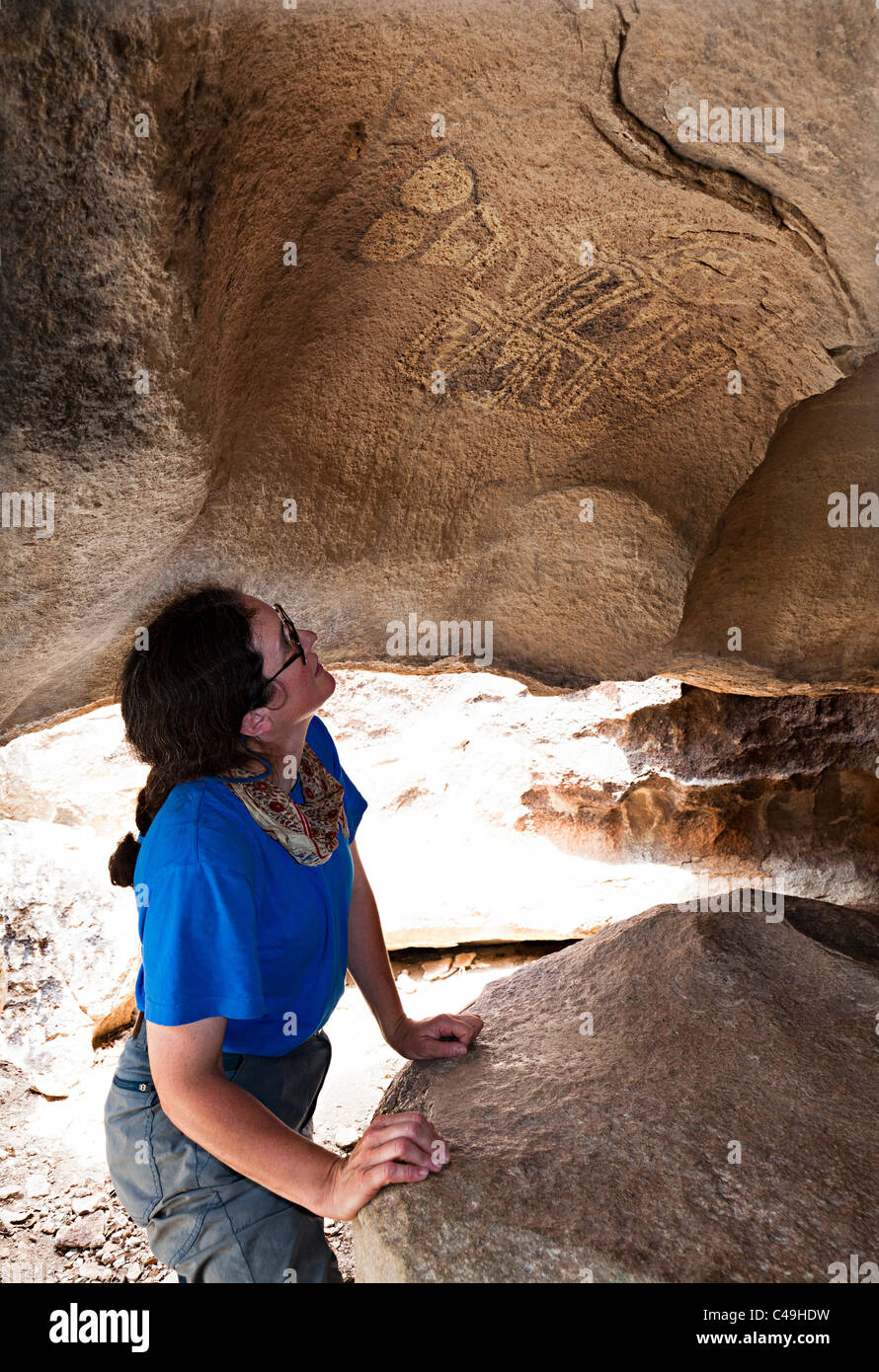 Woman looking at Tlaloc figure pictograph in rock shelter Hueco Tanks State Historic Site Texas USA Stock Photo