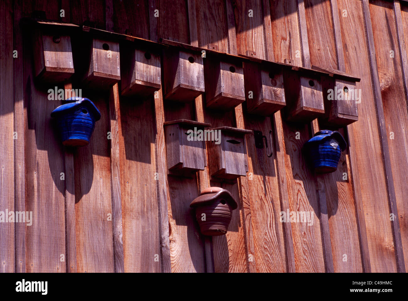 A Row of Bird Houses hanging Side-by-Side on Side of Barn Stock Photo