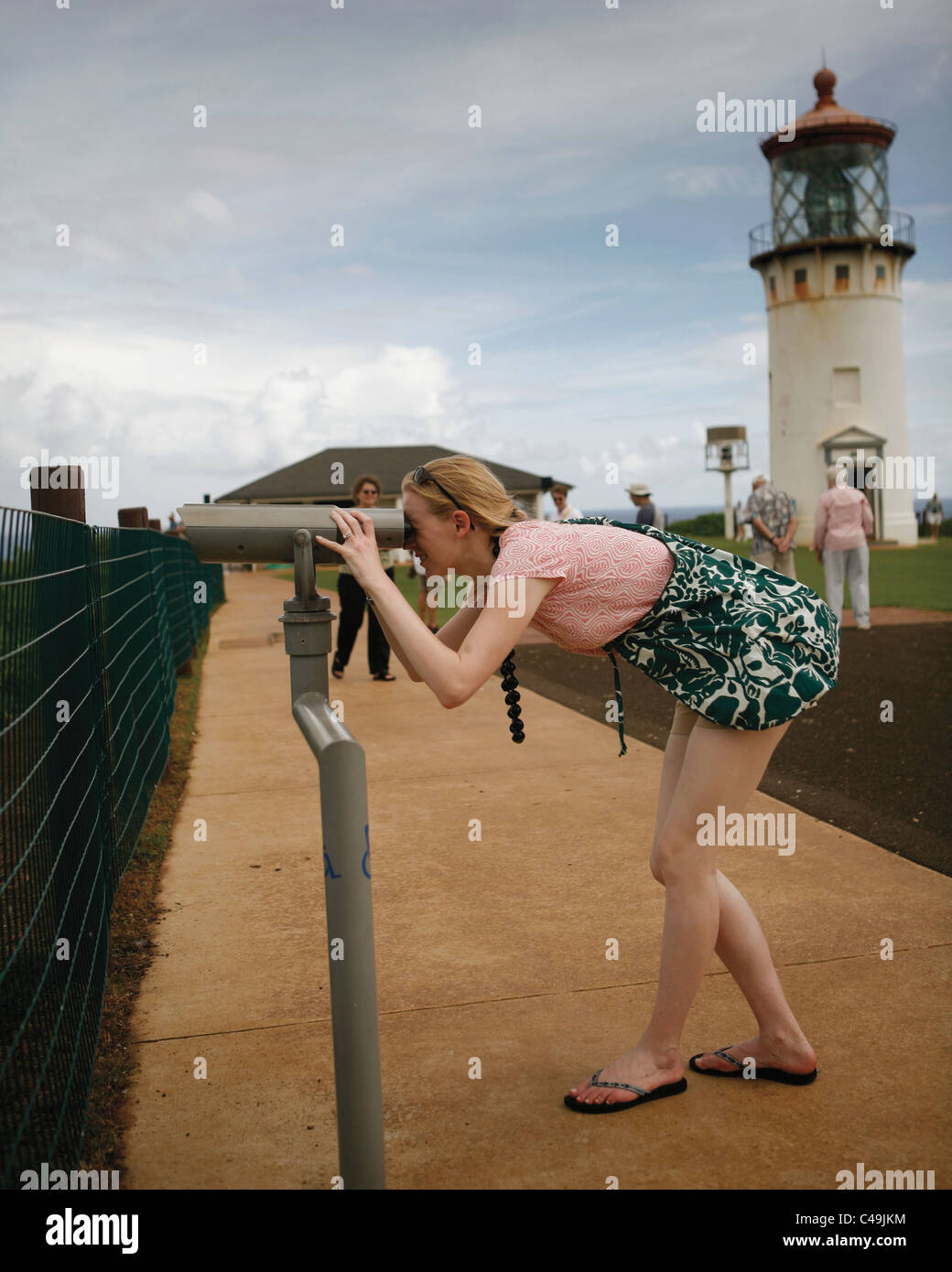 A woman looks into binoculars to view scenic ocean view in Hawaii Stock