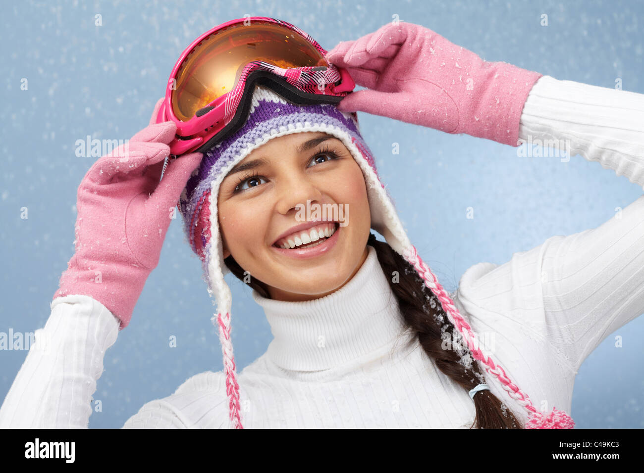 Pretty woman in goggles and knitted winter cap looking upwards with smile Stock Photo