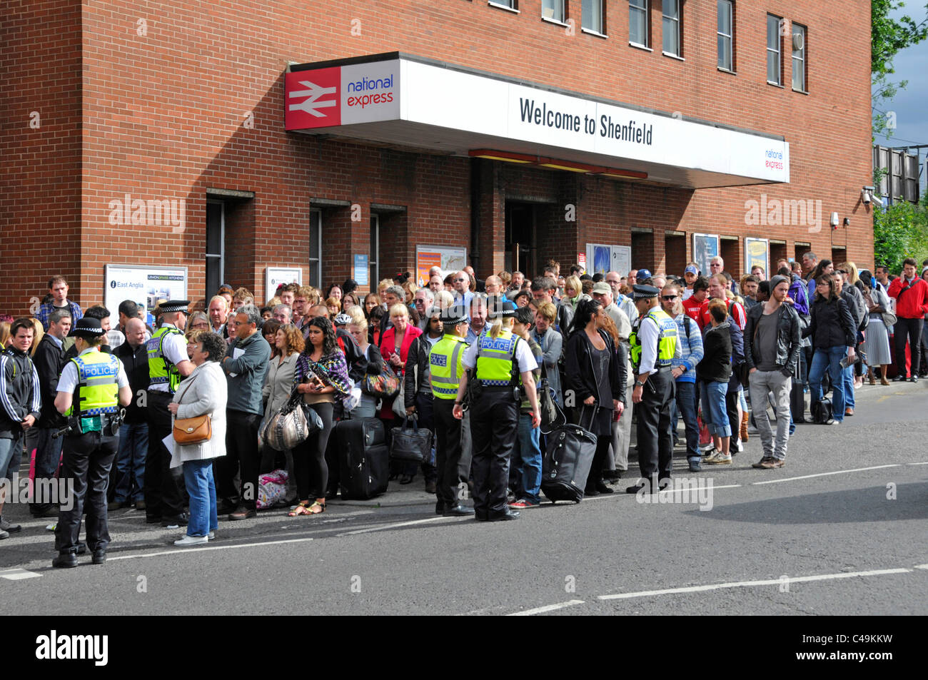 British Transport Police controlling crowds outside railway station waiting for buses after train cancellations & signal failure Stock Photo