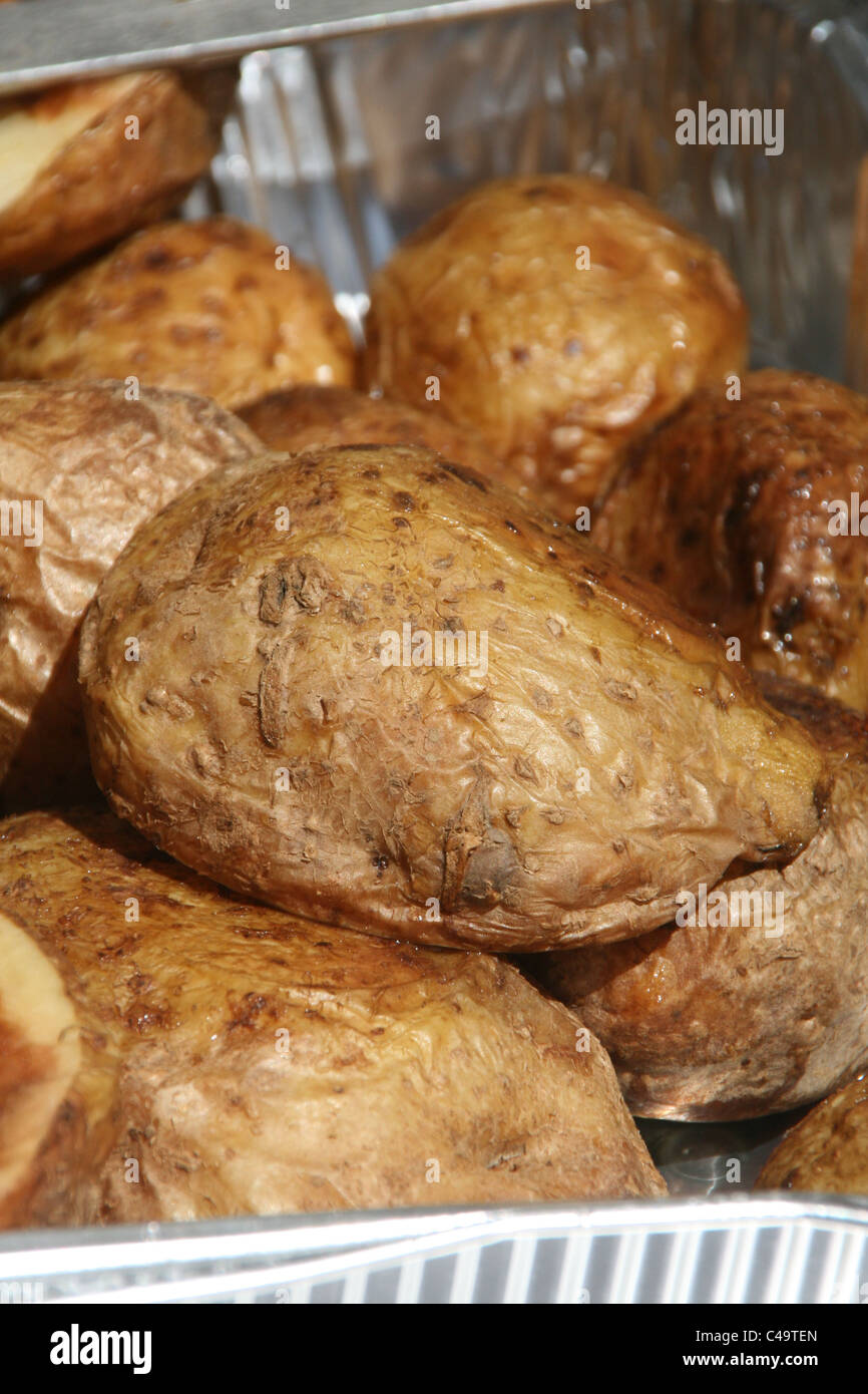 pile of cooked jacket potatoes on silver foil tray Stock Photo Alamy