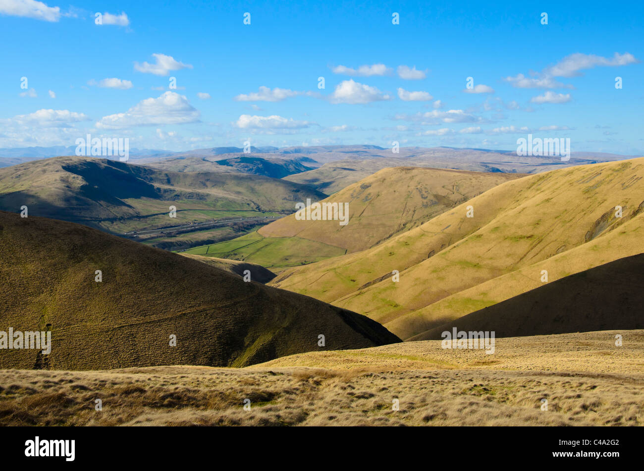 Looking down the valley of Carlin Gill in the Howgill Fells, Cumbria. The M6 motorway beyond and Lake District Fells on horizon Stock Photo