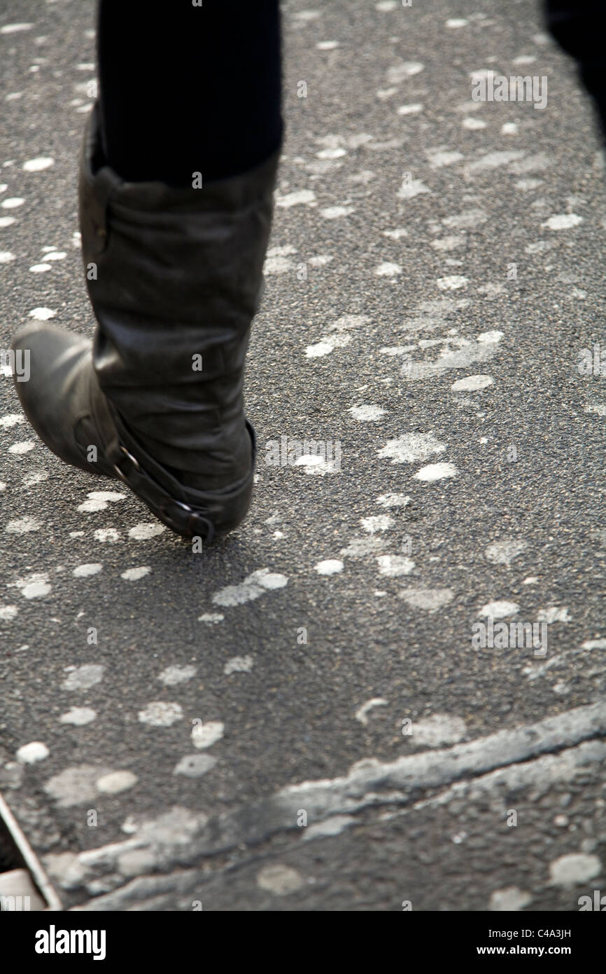 Person / woman 's feet walk / walking past chewing gum stuck on the street / road in Oxford